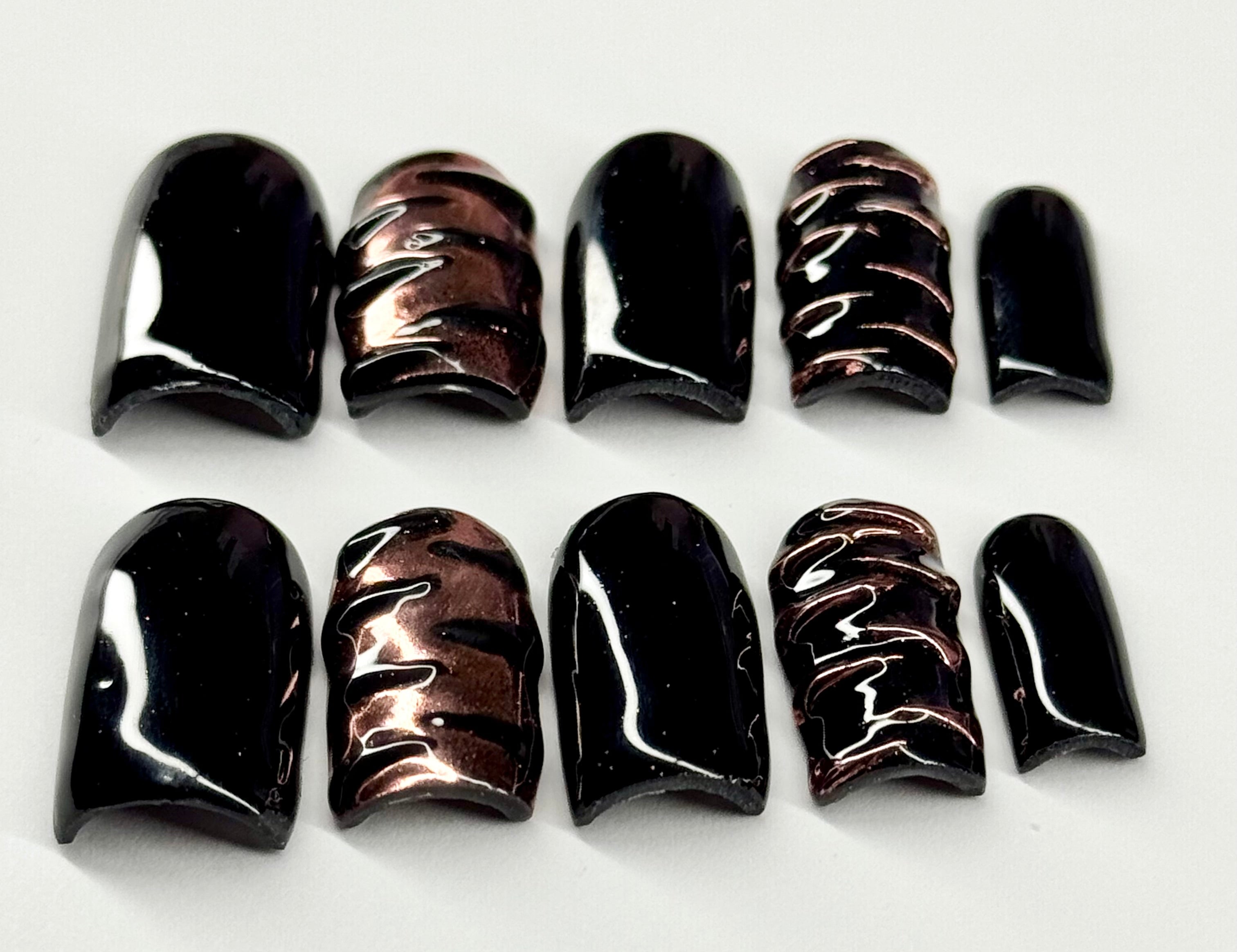 Set of black and brown nail polish samples on a white background