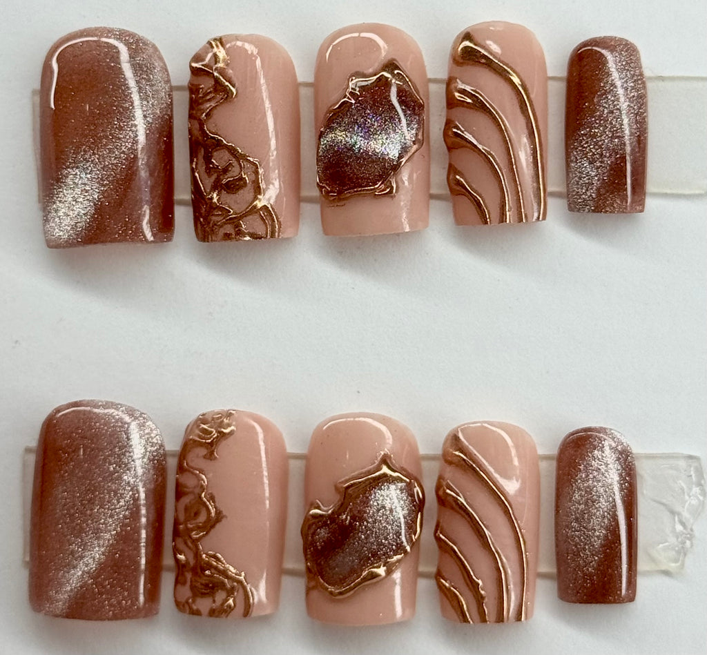 Nail art display with brown and beige designs on a white background