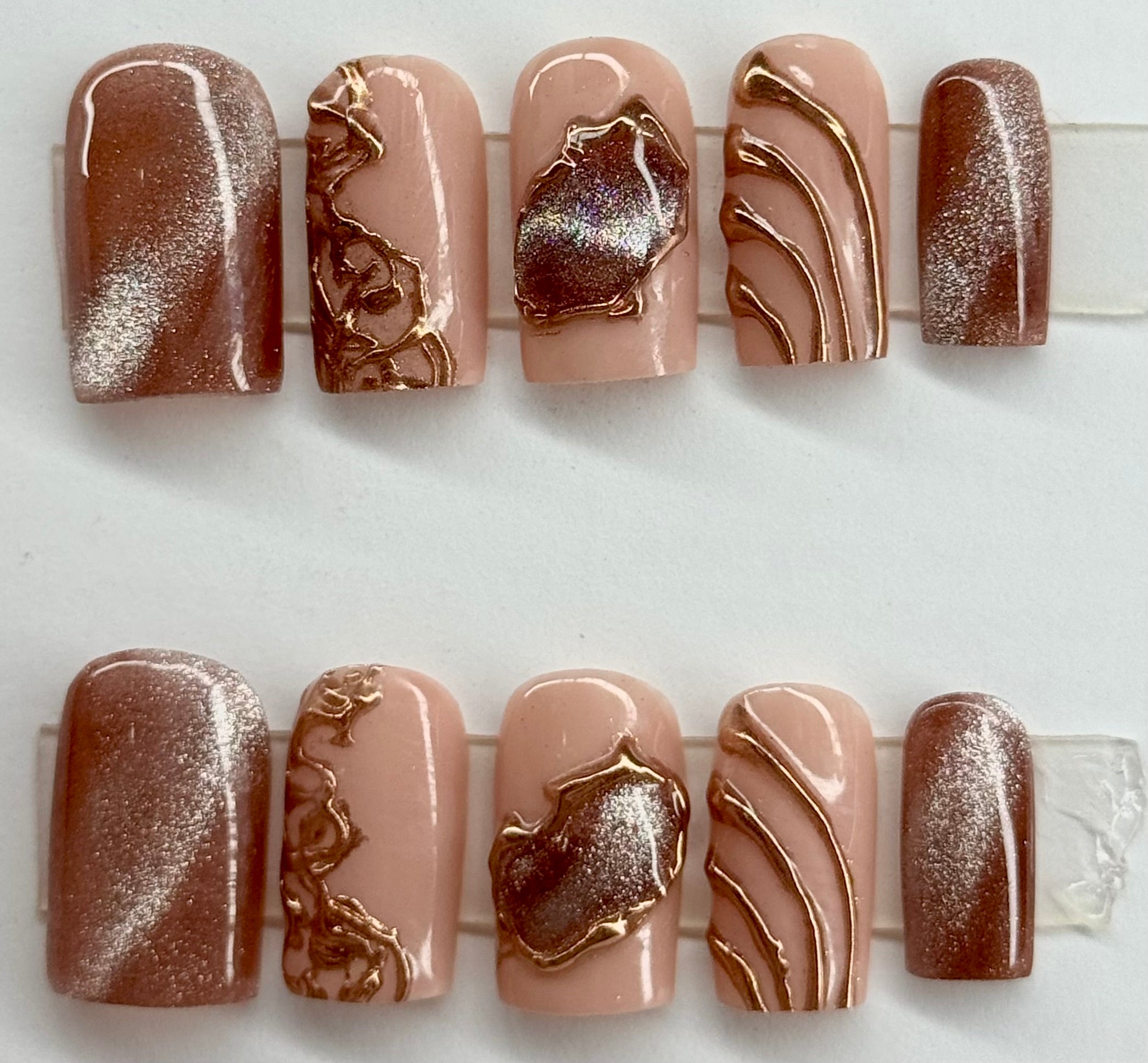 Nail art display with brown and beige designs on a white background