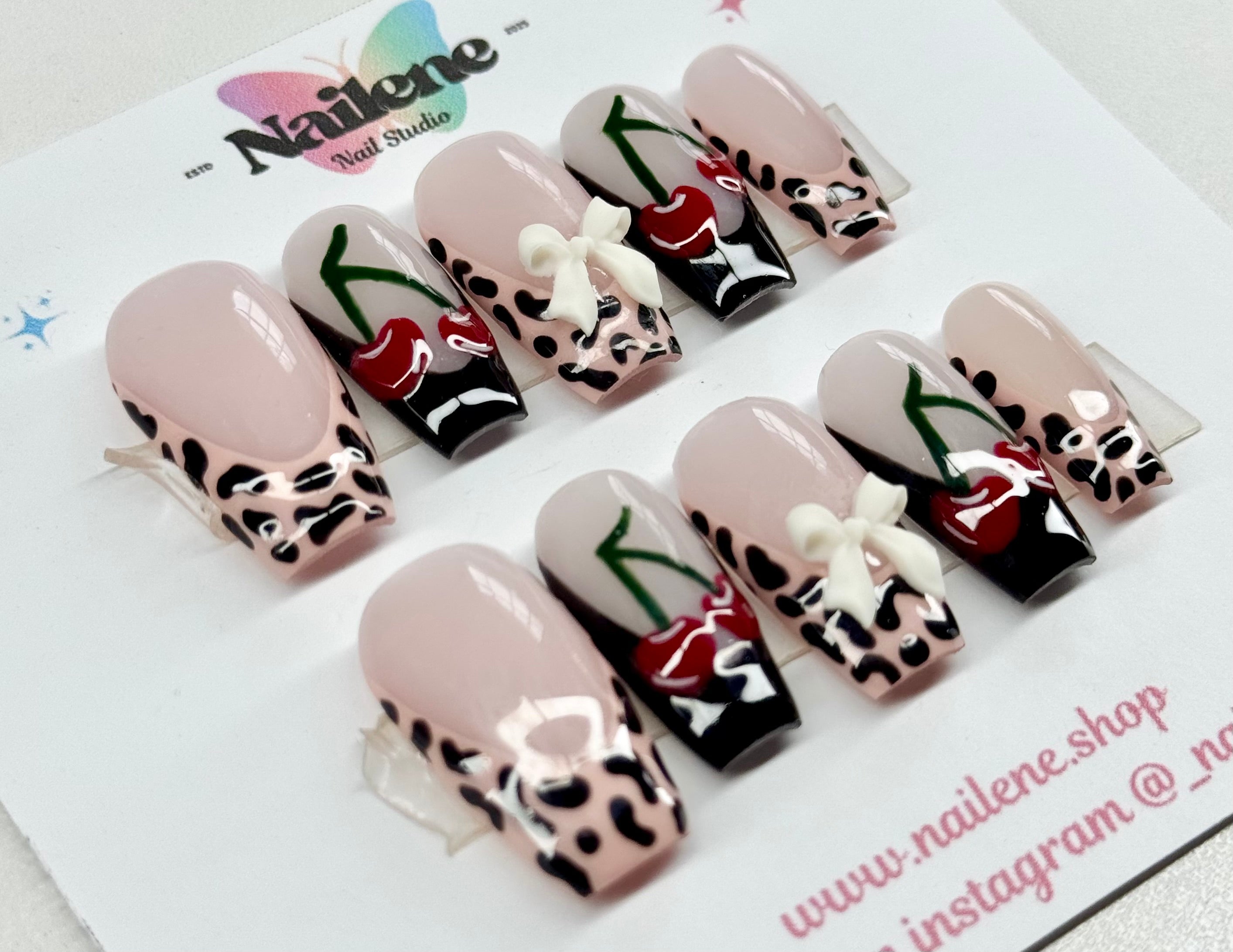 Decorative false nails with animal print and red heart designs on a Nailene branded card.