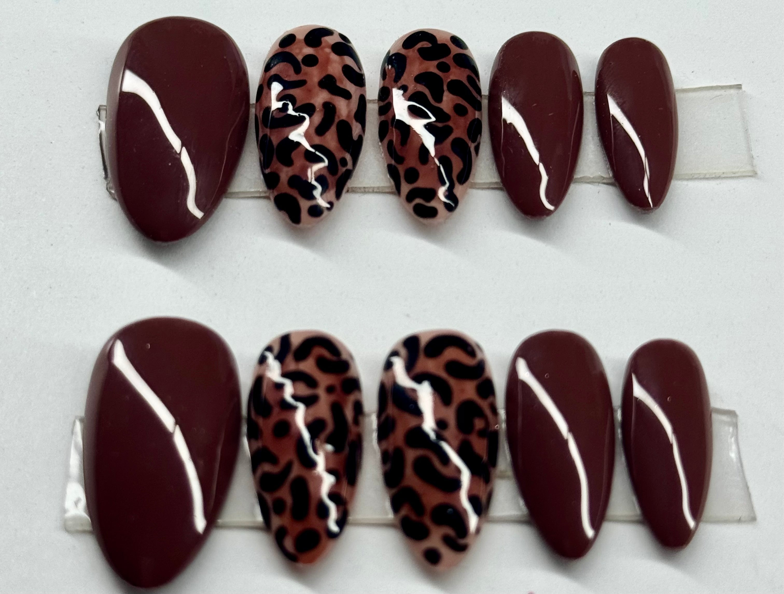 Set of false nails with leopard print and white stripes on a white background