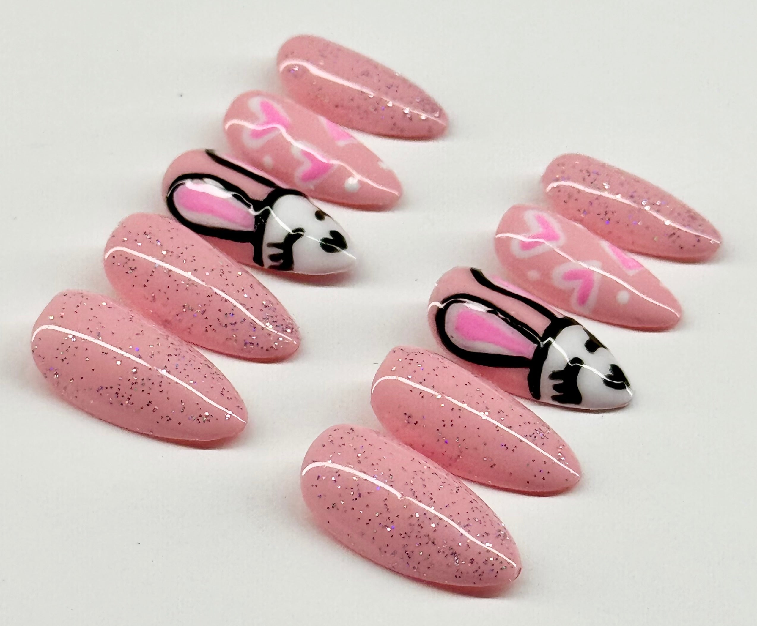 Pink glittery nail art designs with decorative elements on a white background