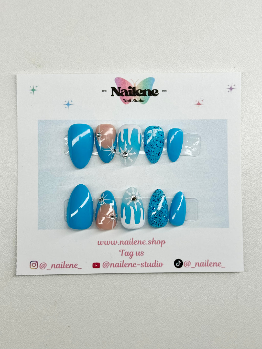 Set of blue and white nail art designs on a display card with Nailene branding.
