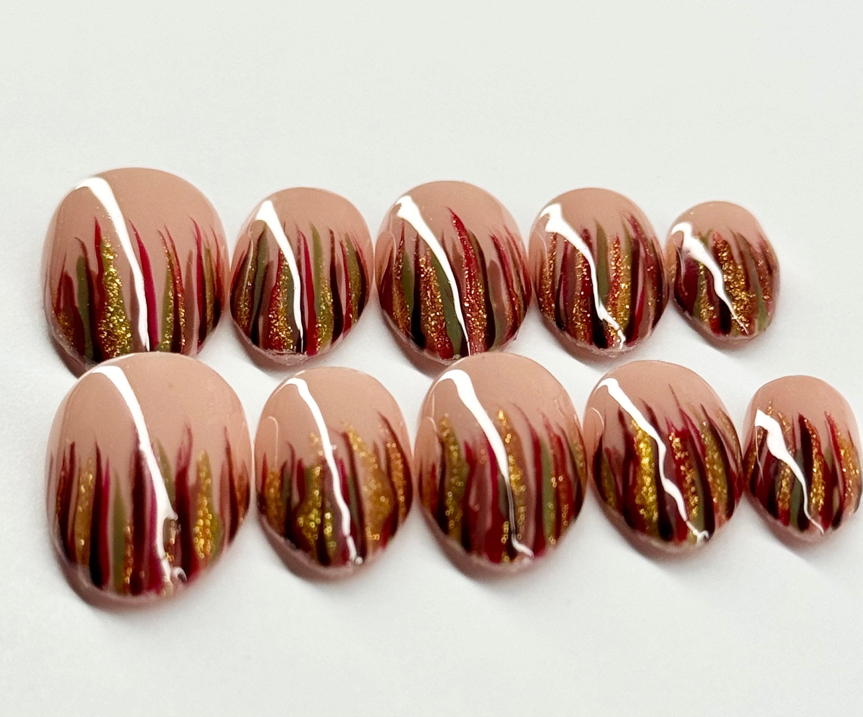 Nail art design with gold and red patterns on a white background