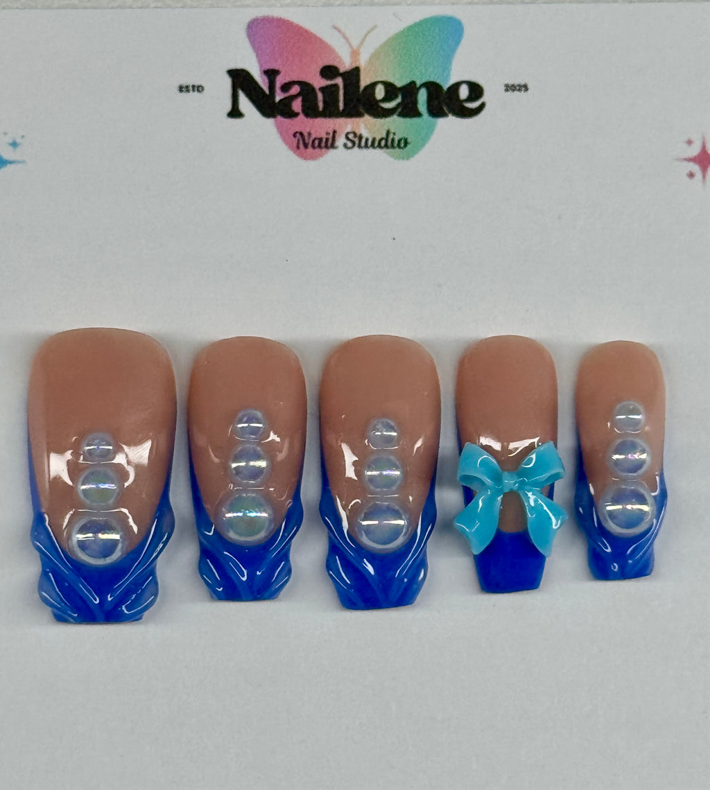 Set of false nails with blue tips and a bow design, branded as Nailene Nail Studio.