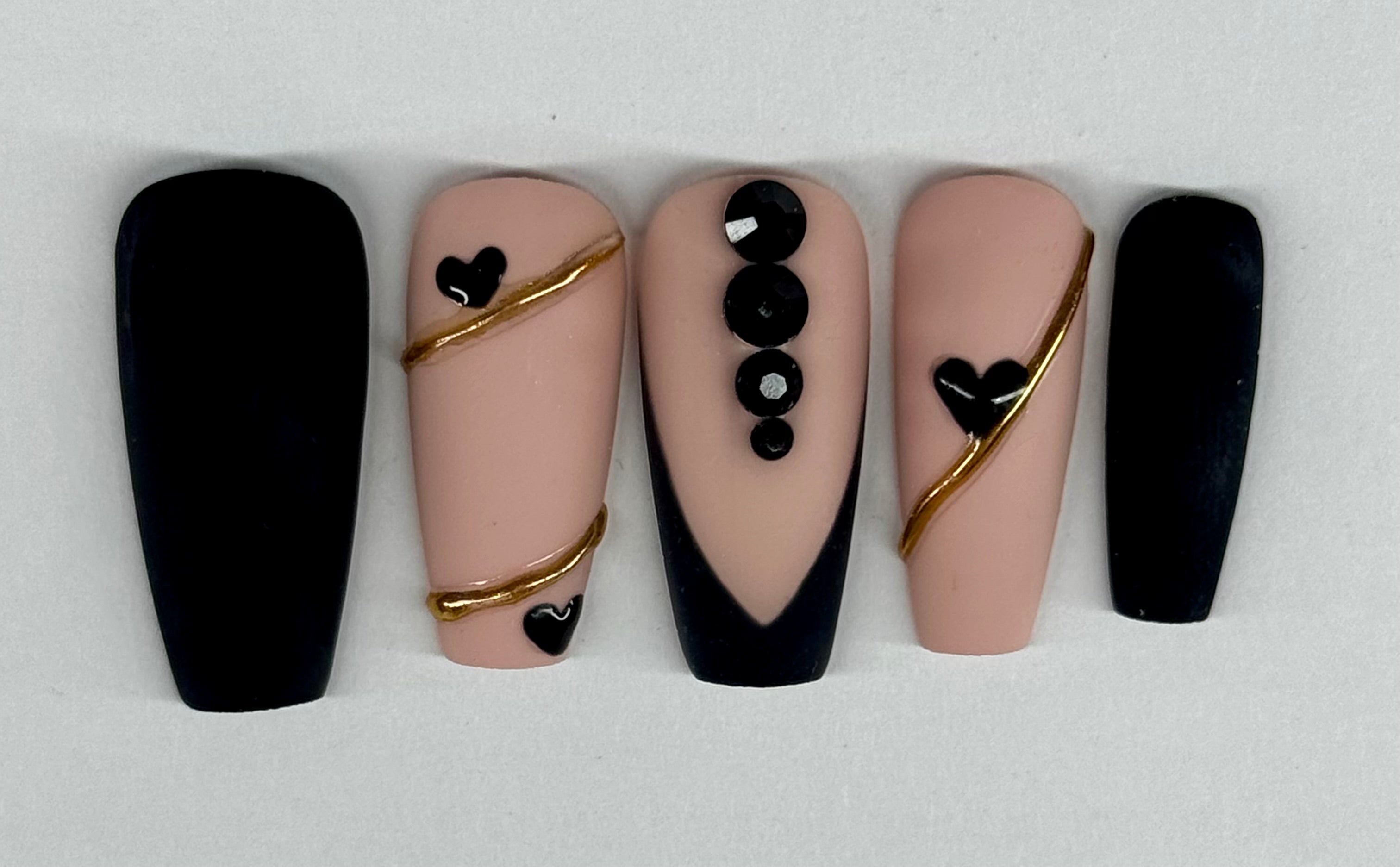 Nail art display with black, gold, and beige designs on a white background