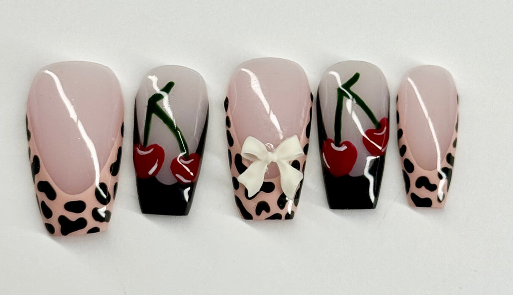 Five nail art designs with cherries and leopard print patterns on a white background
