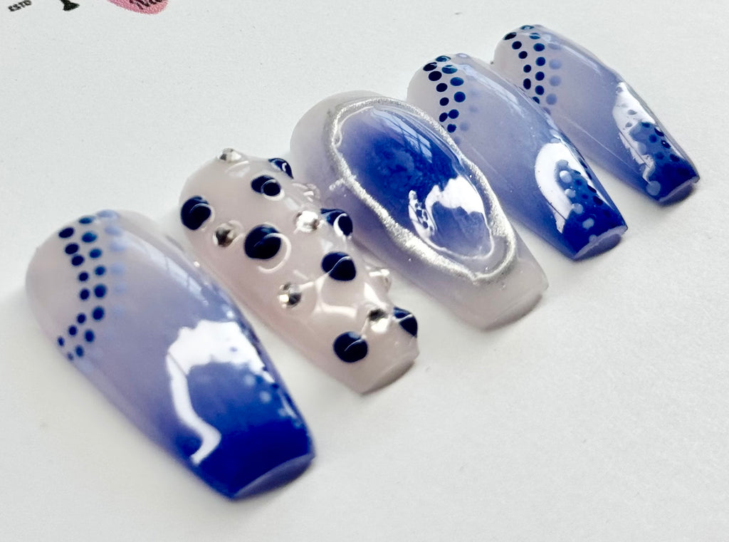 Nail art display with blue and white design on a white background