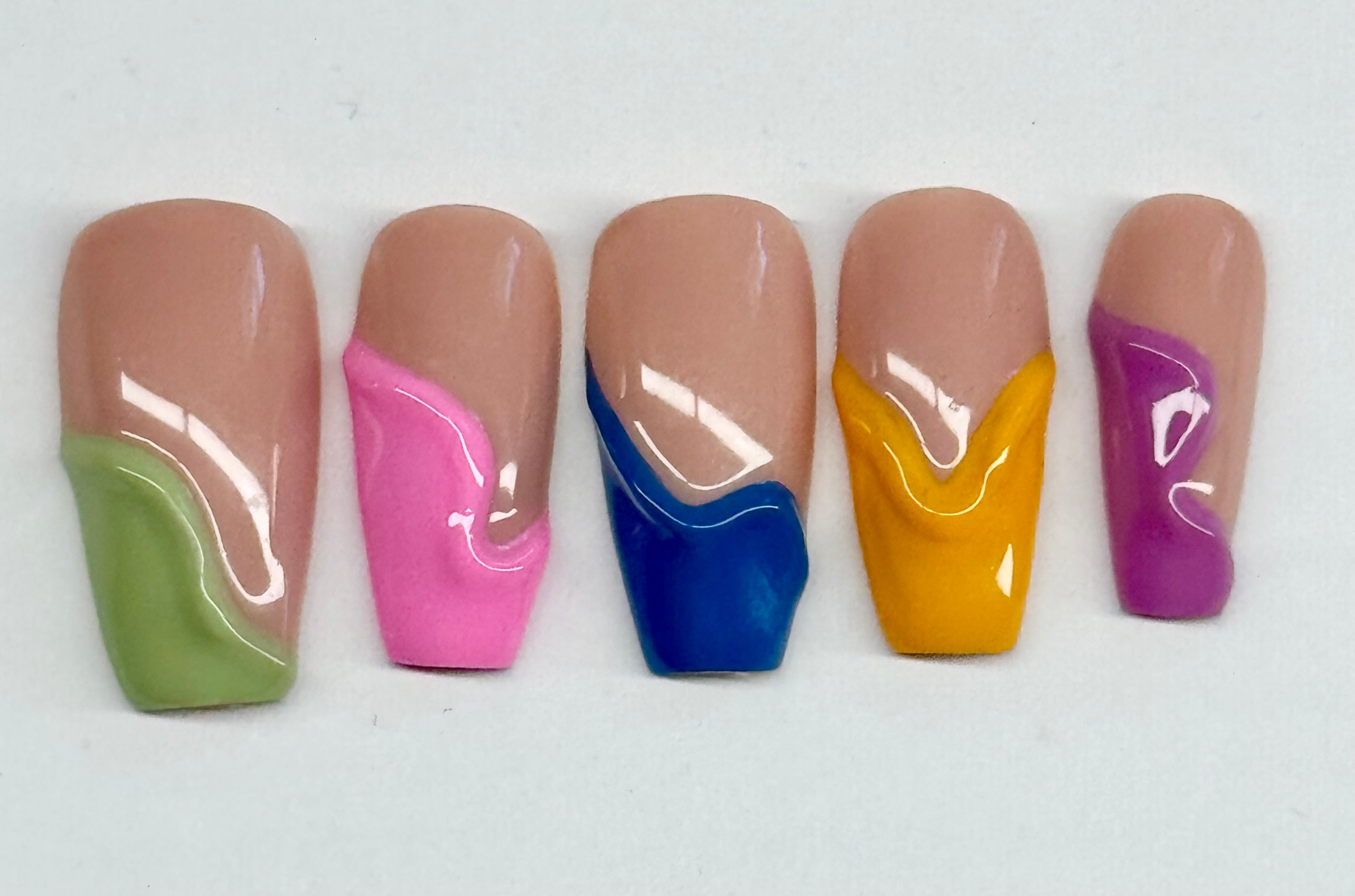 Set of five artificial nails with multicolored designs on a white background