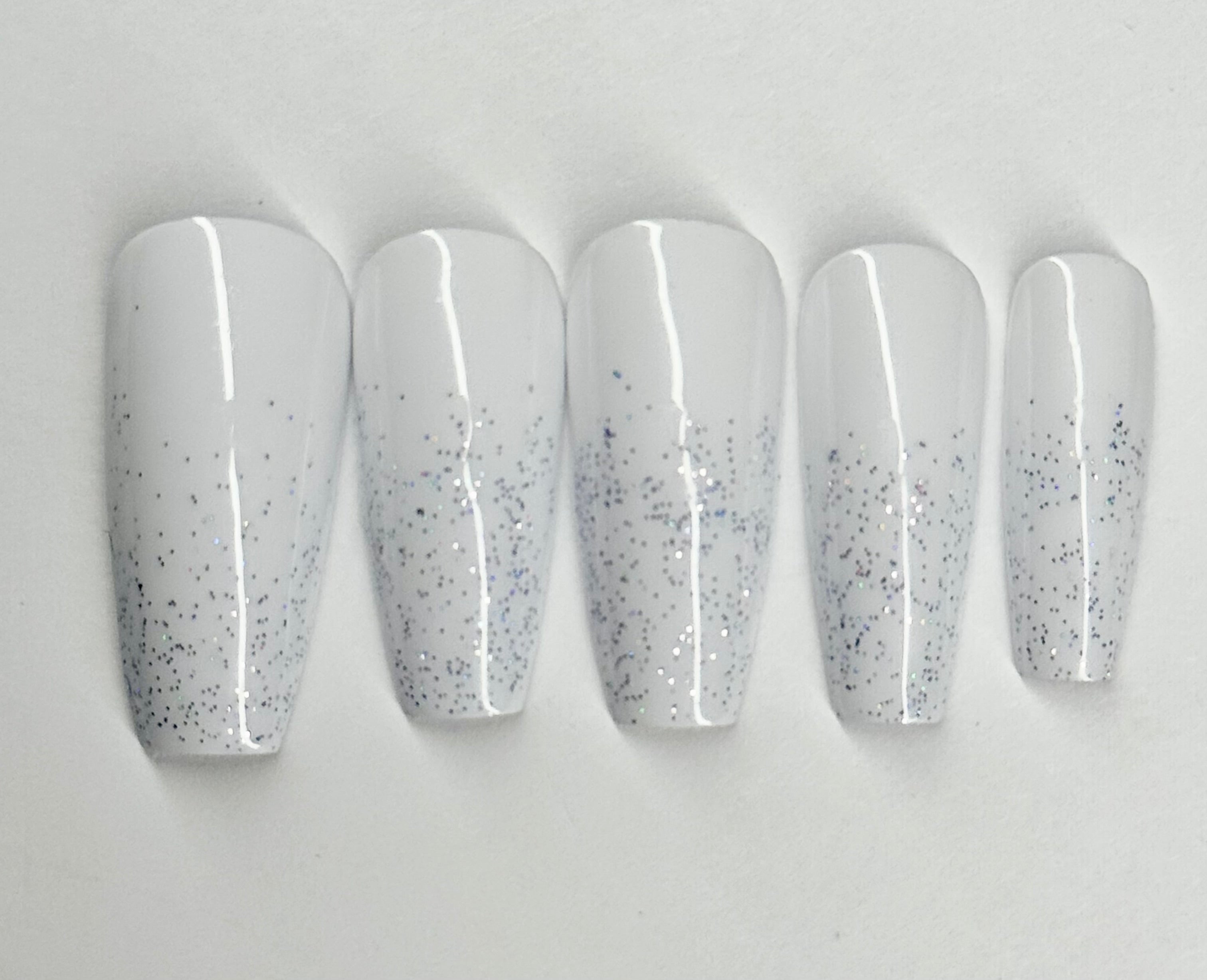 Set of five white nail polish with glittery specks on a light gray background