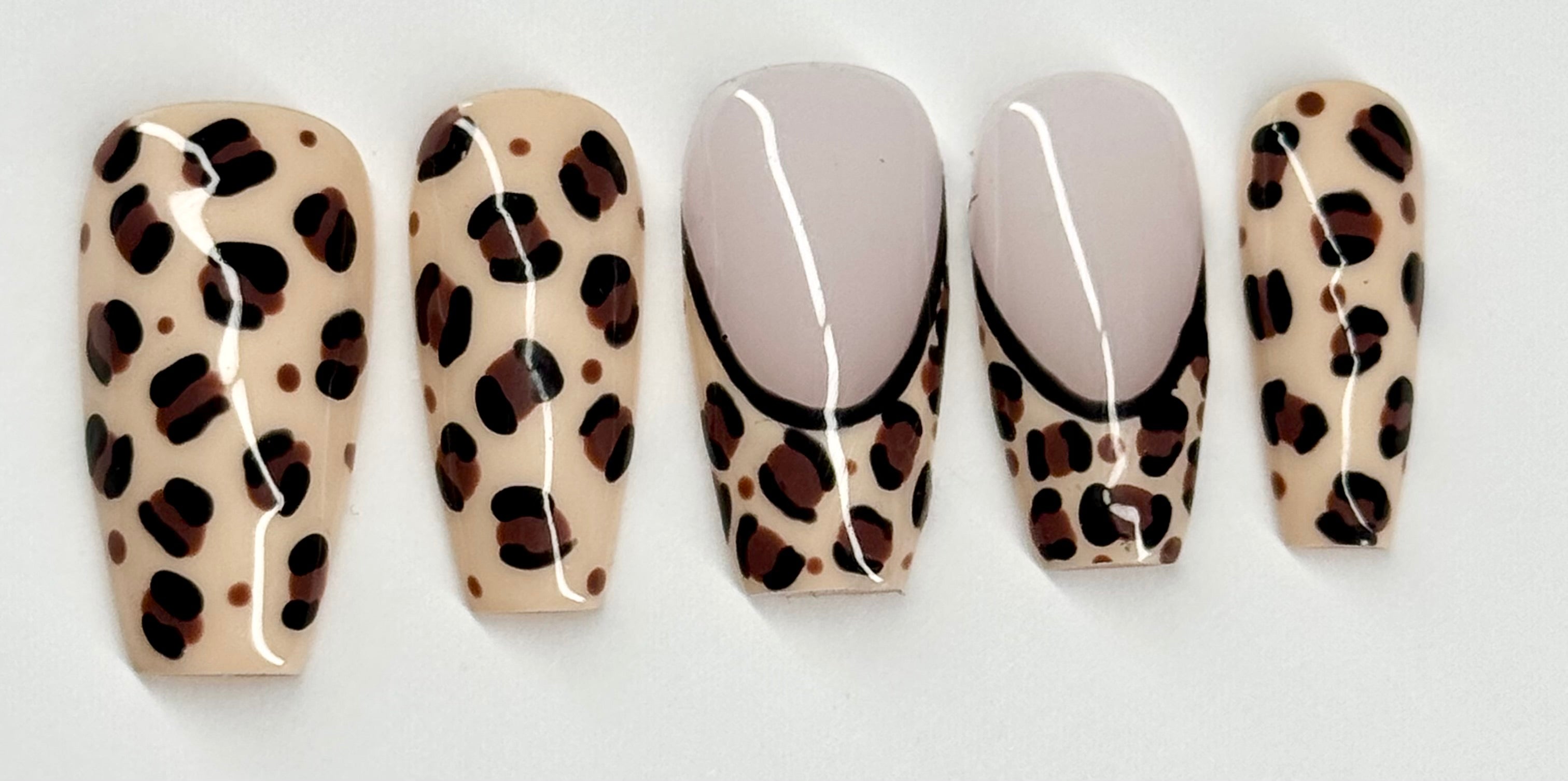 Five false nails with leopard print design on a white background