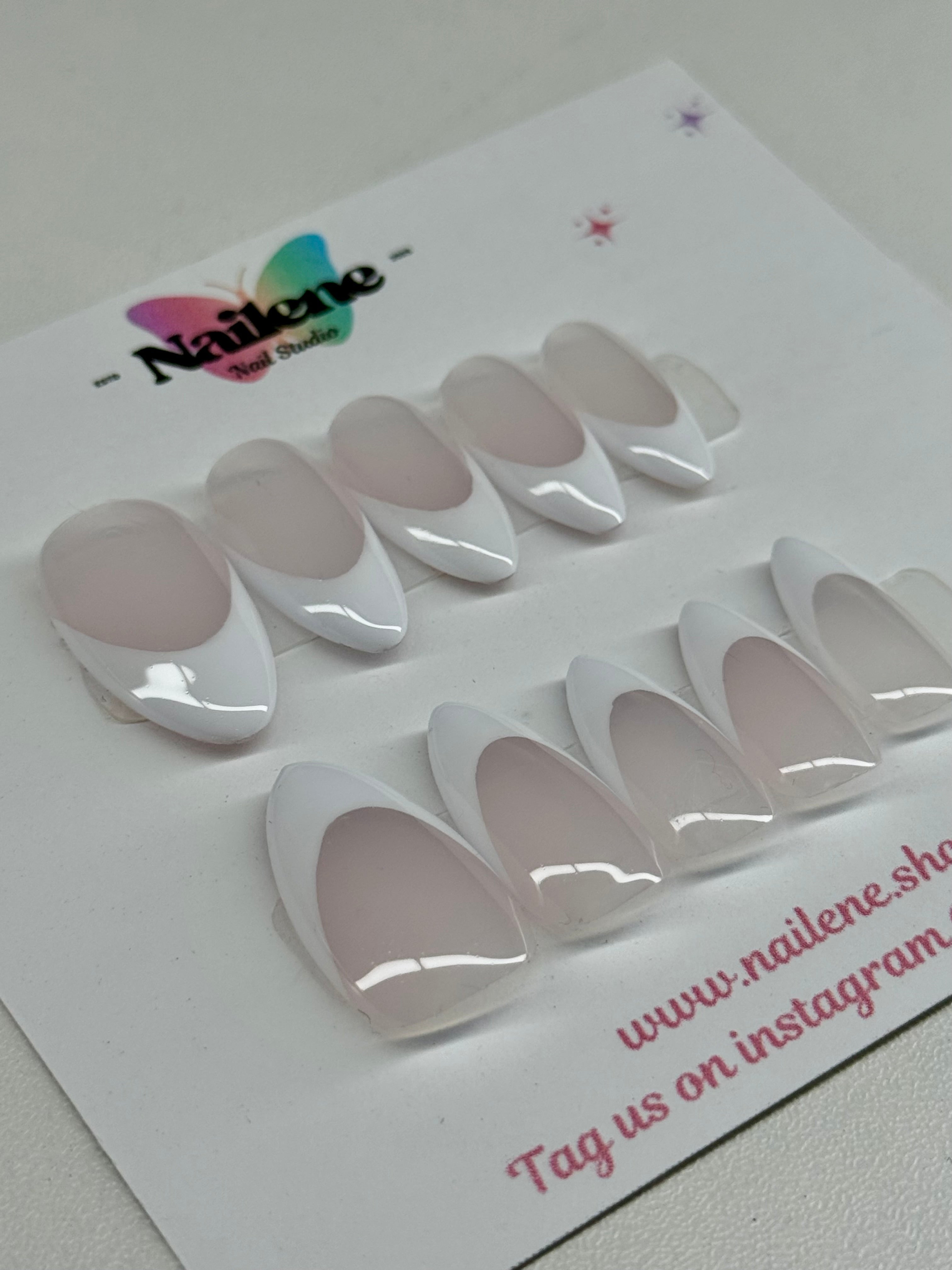 Set of white nail extensions on a Nailene branded card.
