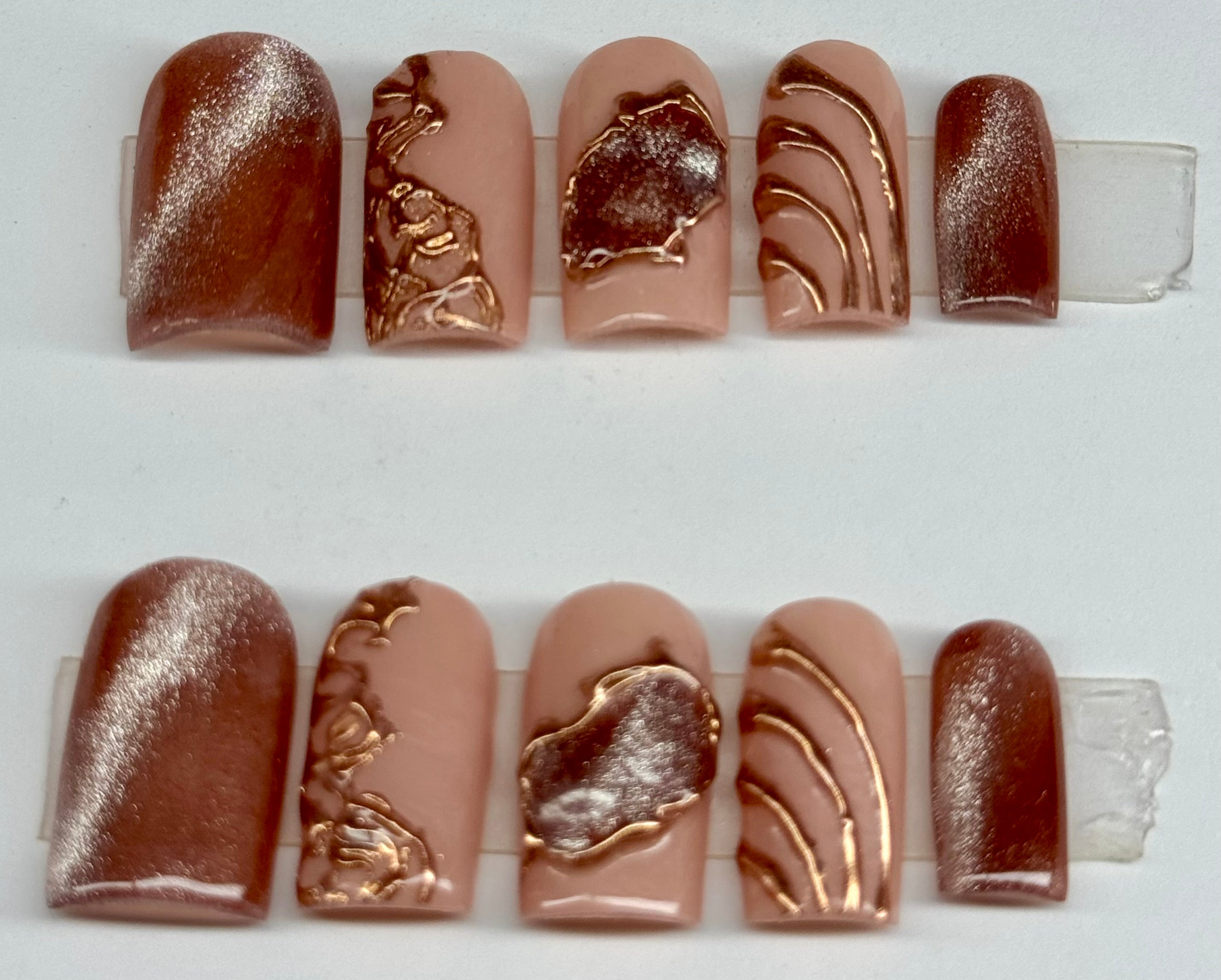 Set of nail art samples with metallic designs on a white background