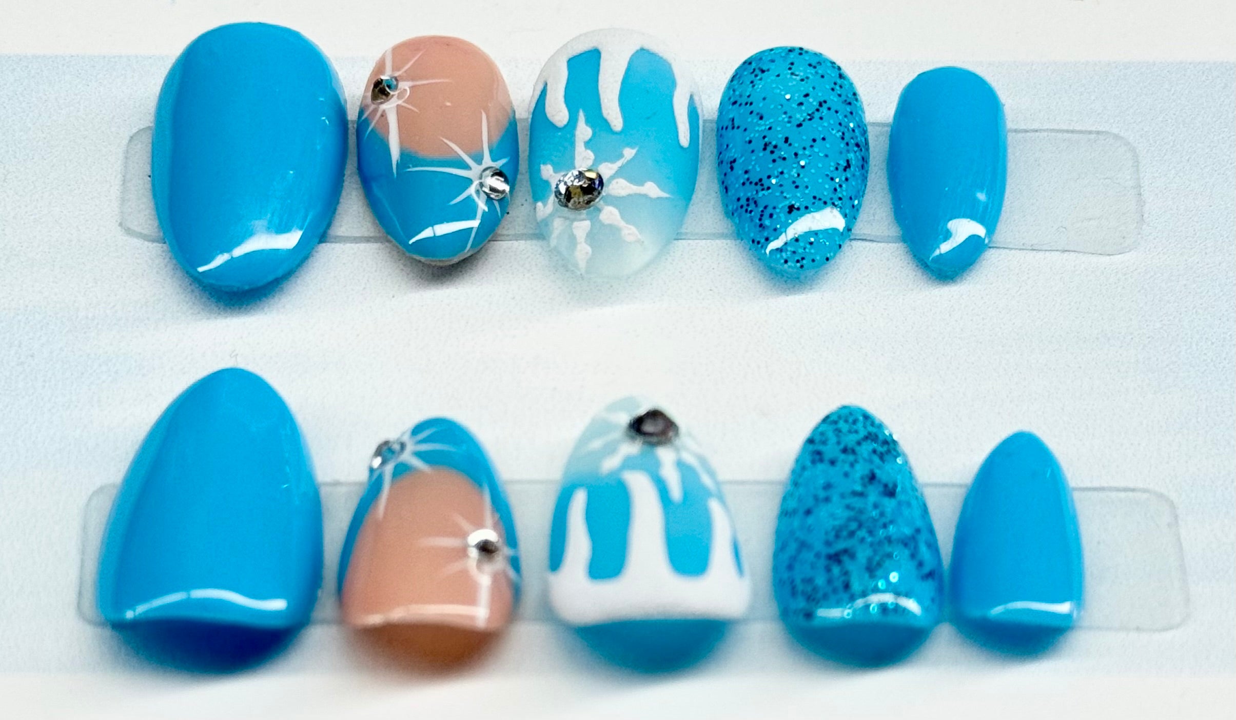 Set of blue and white nail art designs on a clear display stand.