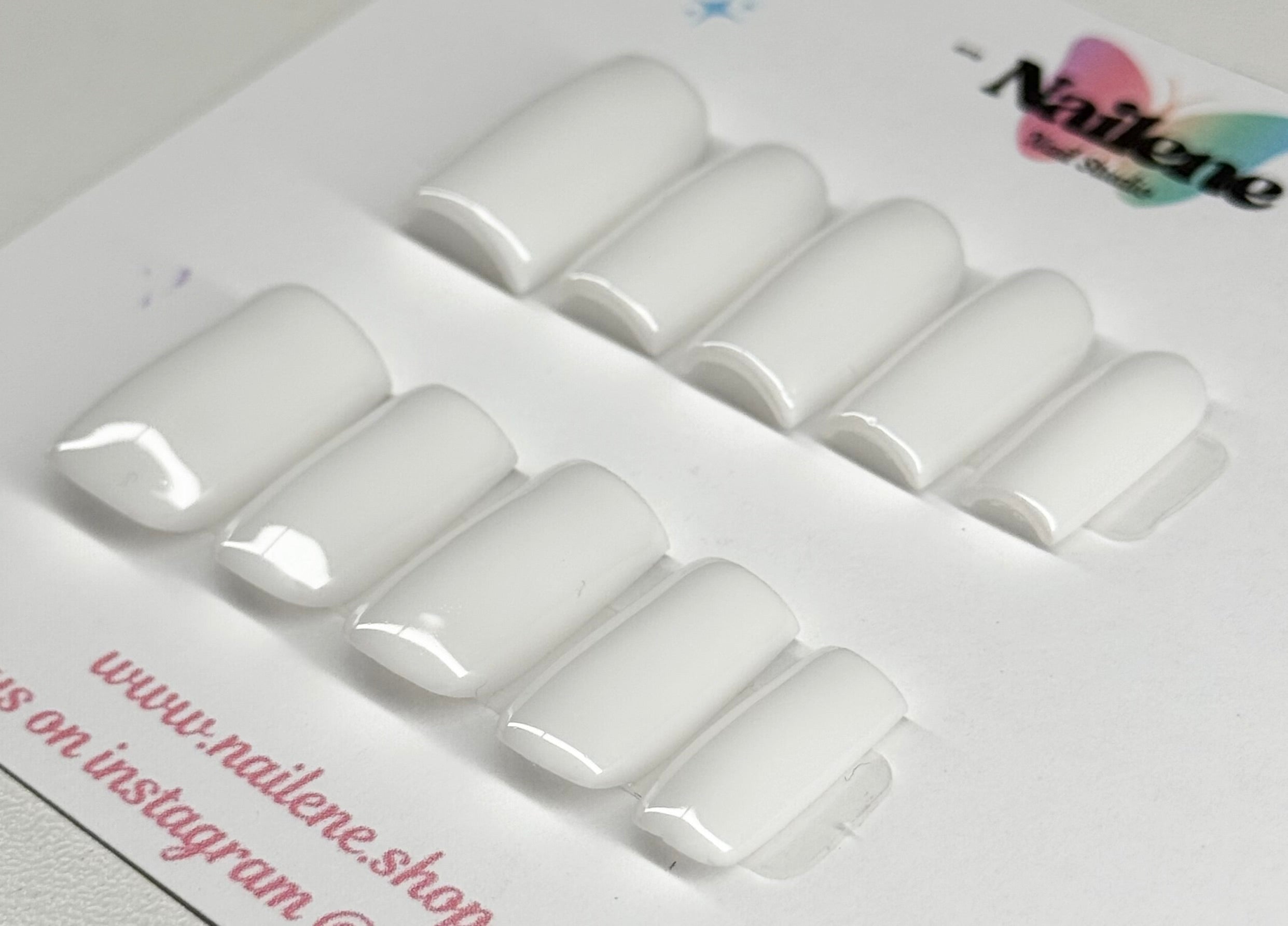 Set of white nail extensions on a branded tray with 'Nailene' branding.