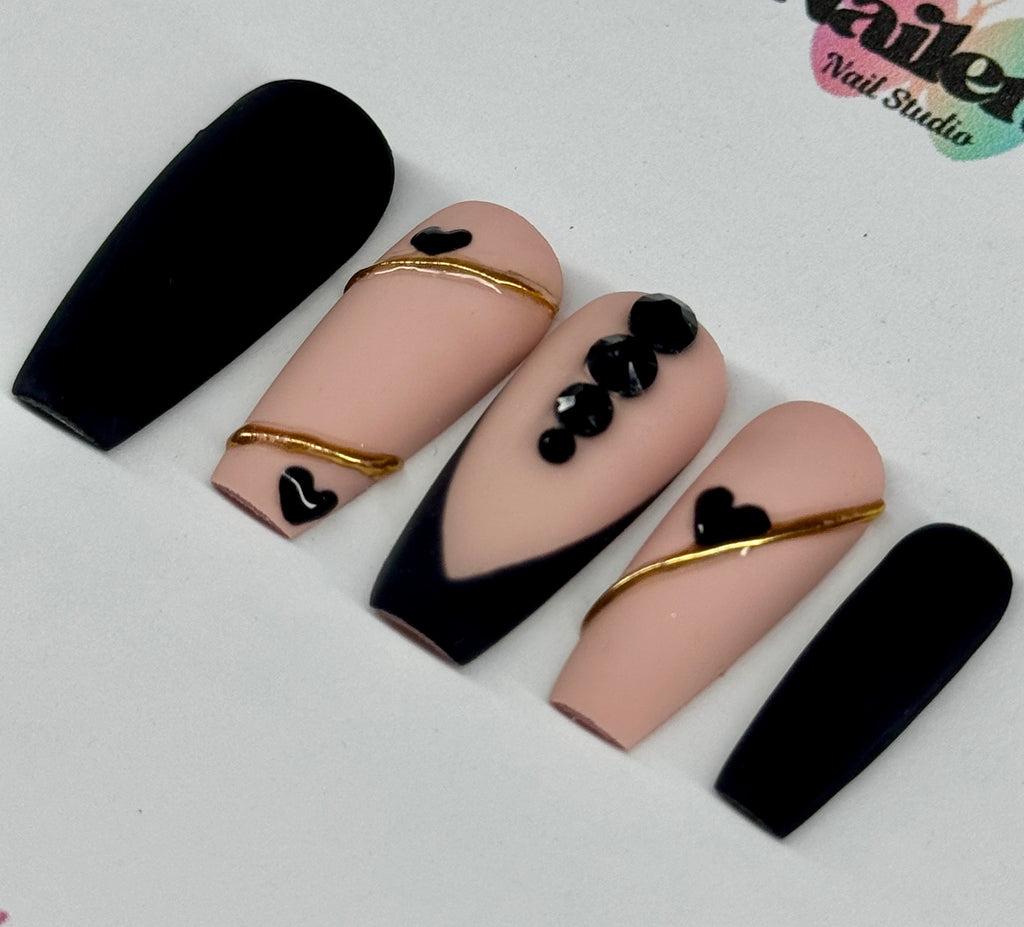Nail art design with black, gold, and pink on a white background