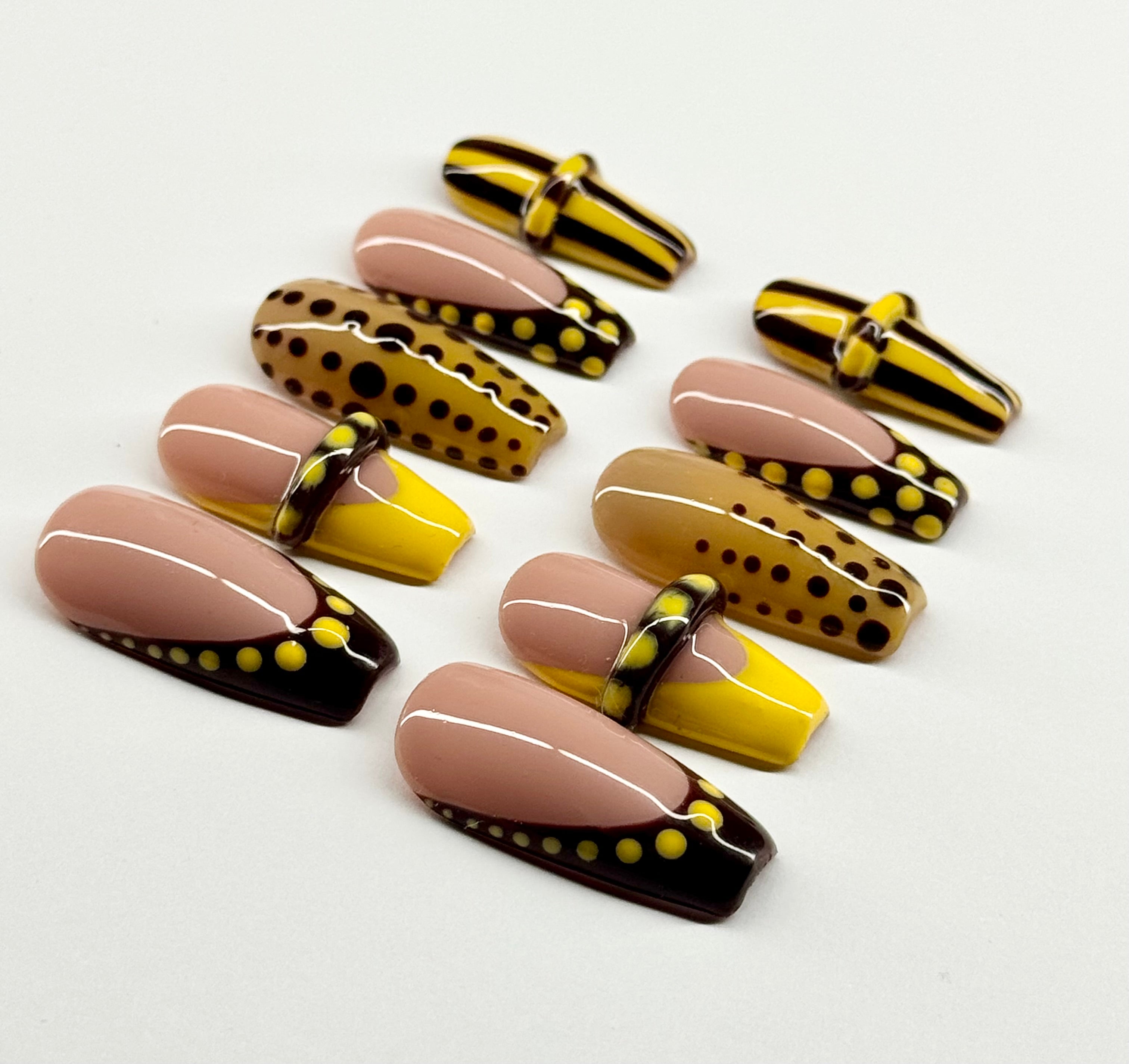 Set of nail art designs with gold, black, and yellow patterns on a white background