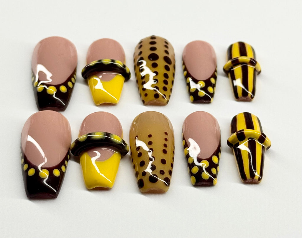 Set of nail art designs with brown, yellow, and black patterns on a white background