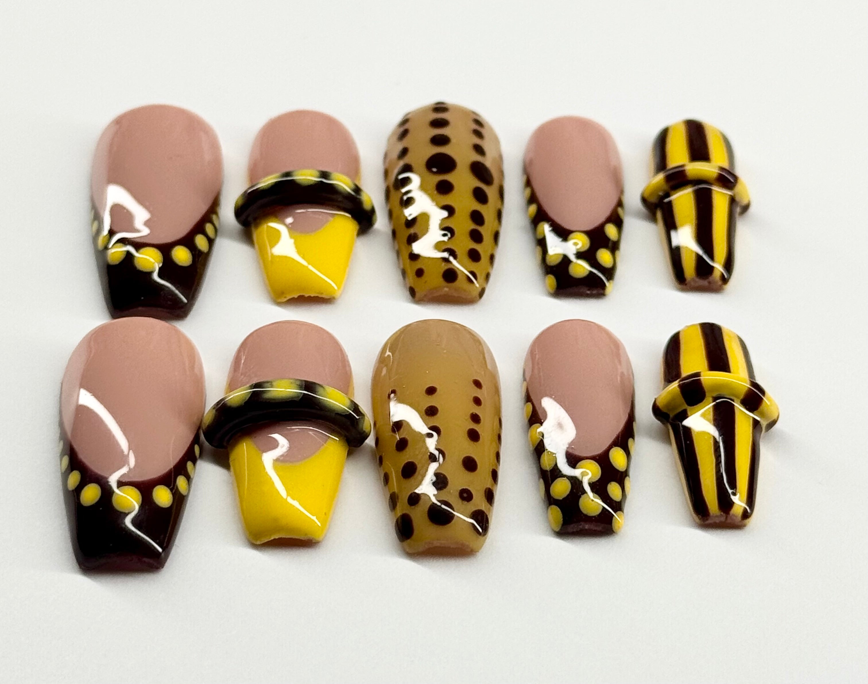 Set of nail art designs with brown, yellow, and black patterns on a white background