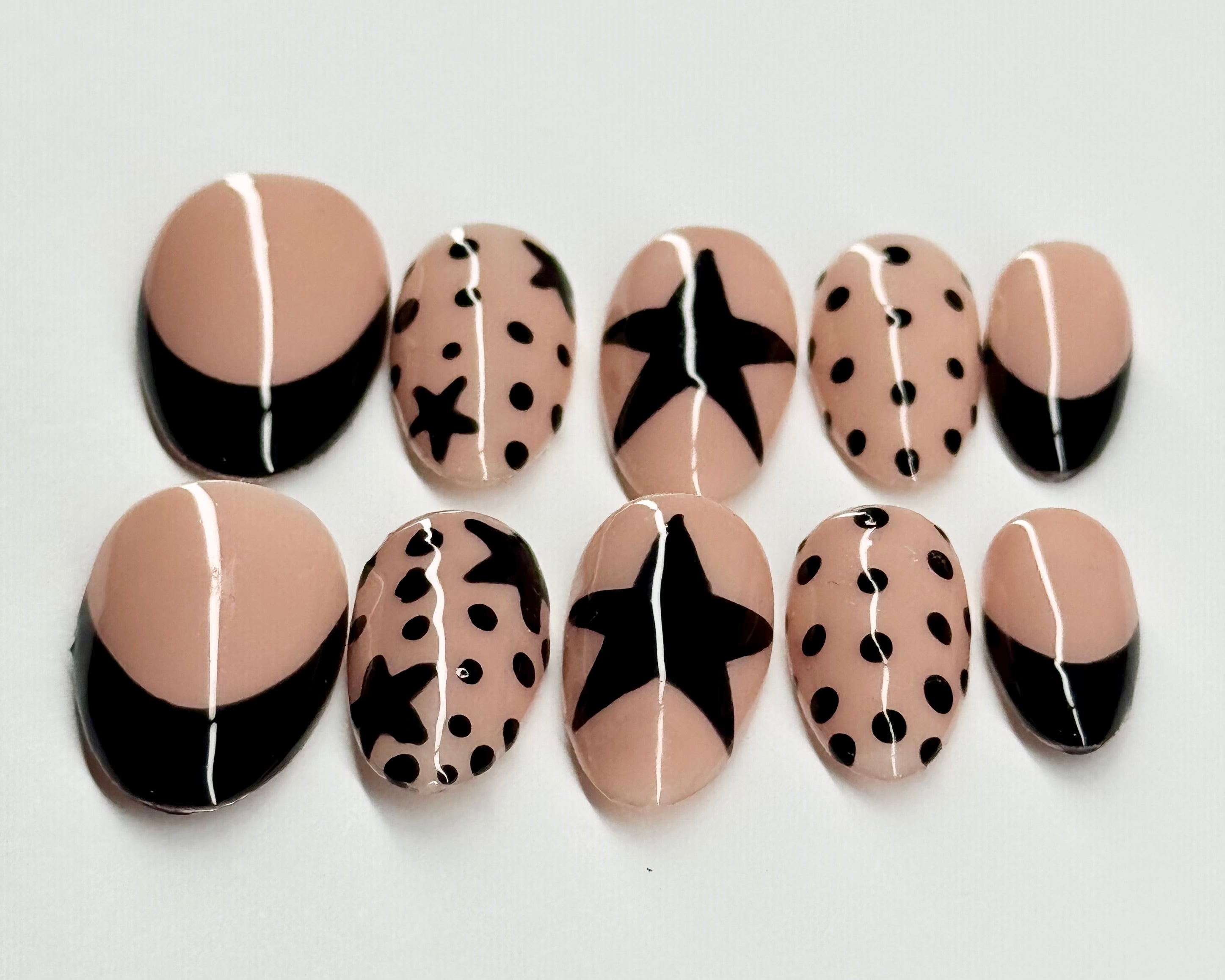 Set of nail art designs with beige, black, and white patterns on a light gray background