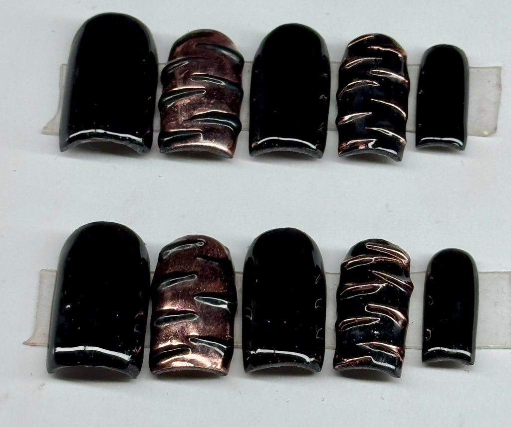 Set of black and bronze nail wraps on a white background