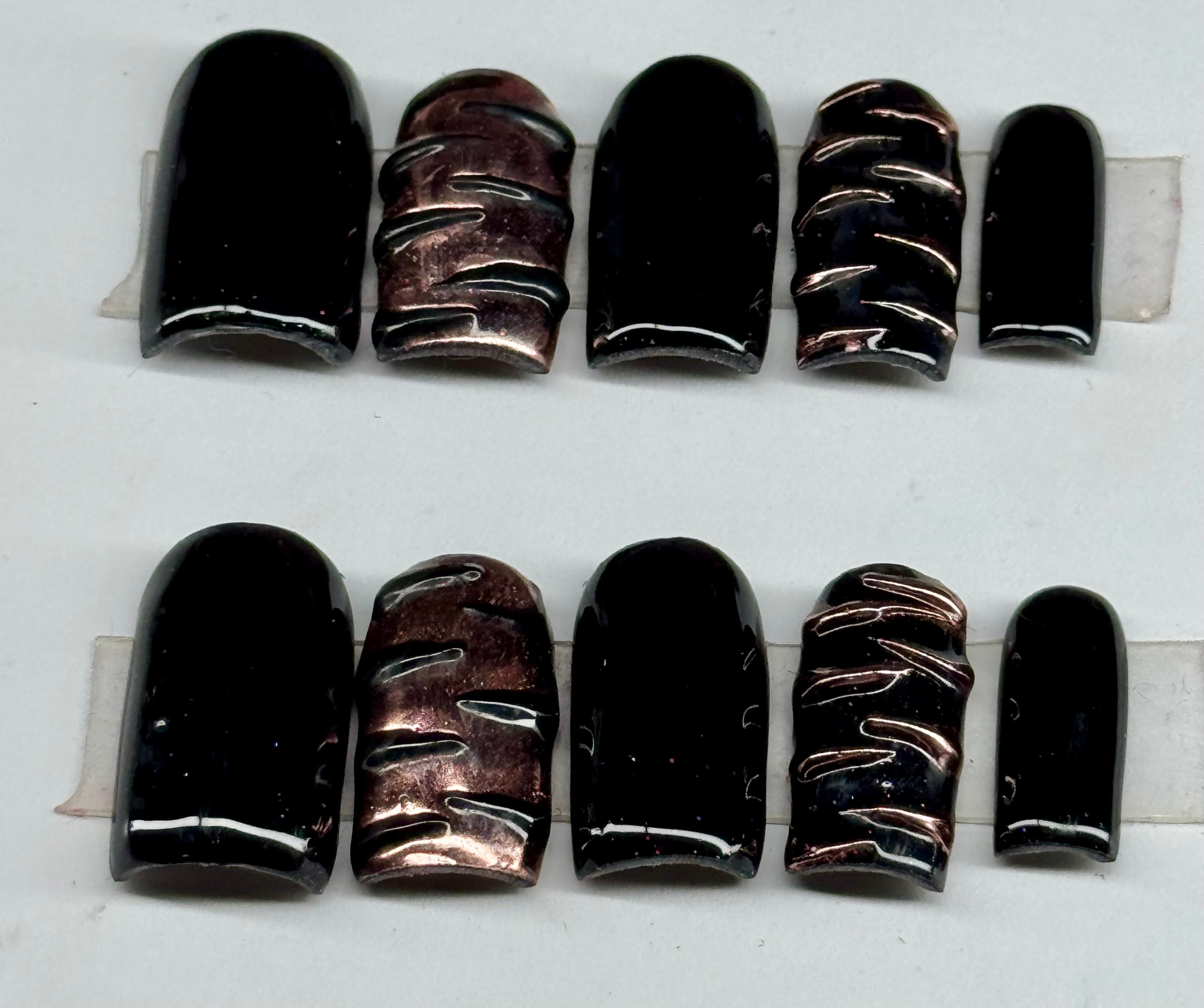 Set of black and bronze nail wraps on a white background