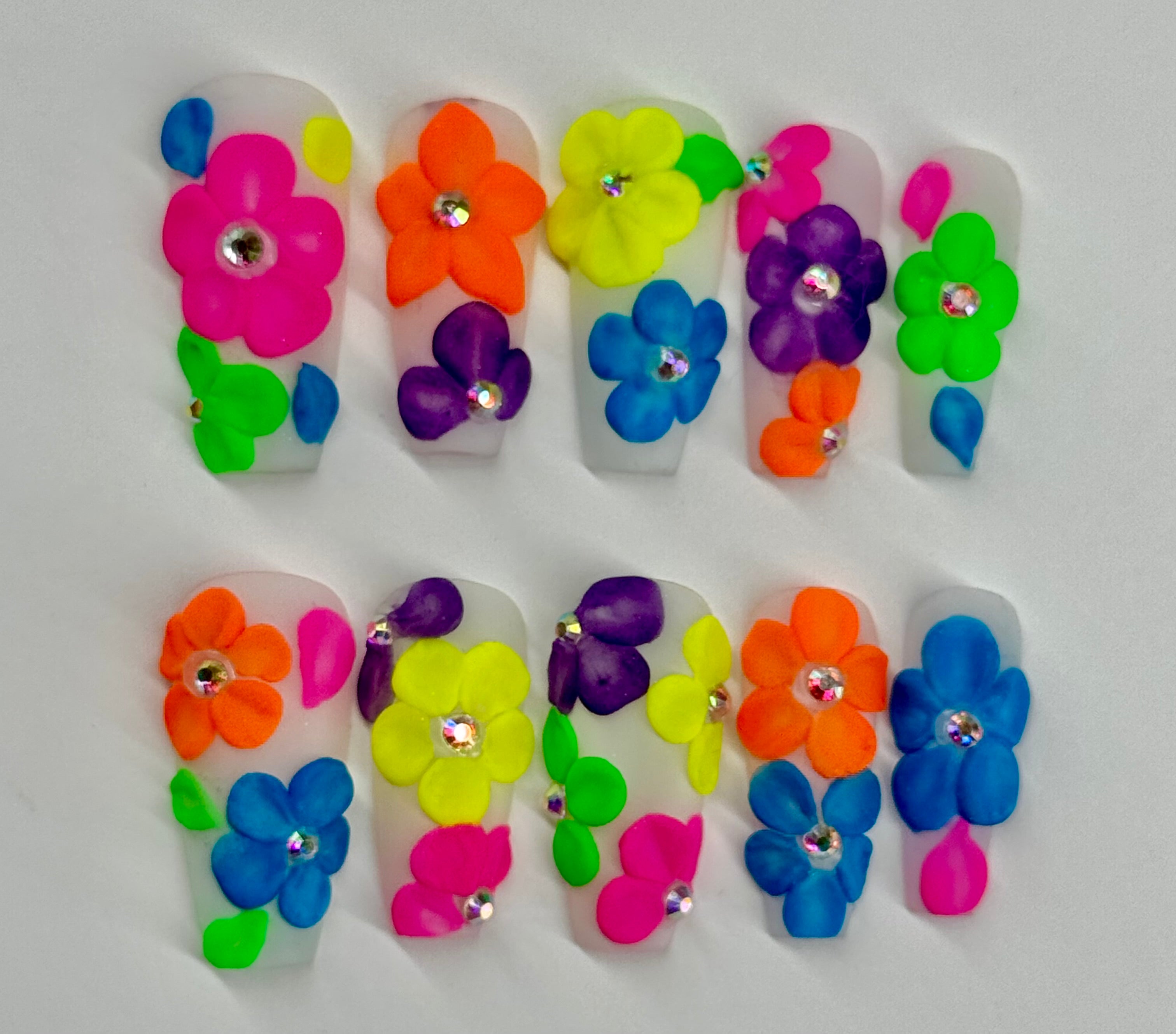 Colorful flower-shaped nail art designs on a white background