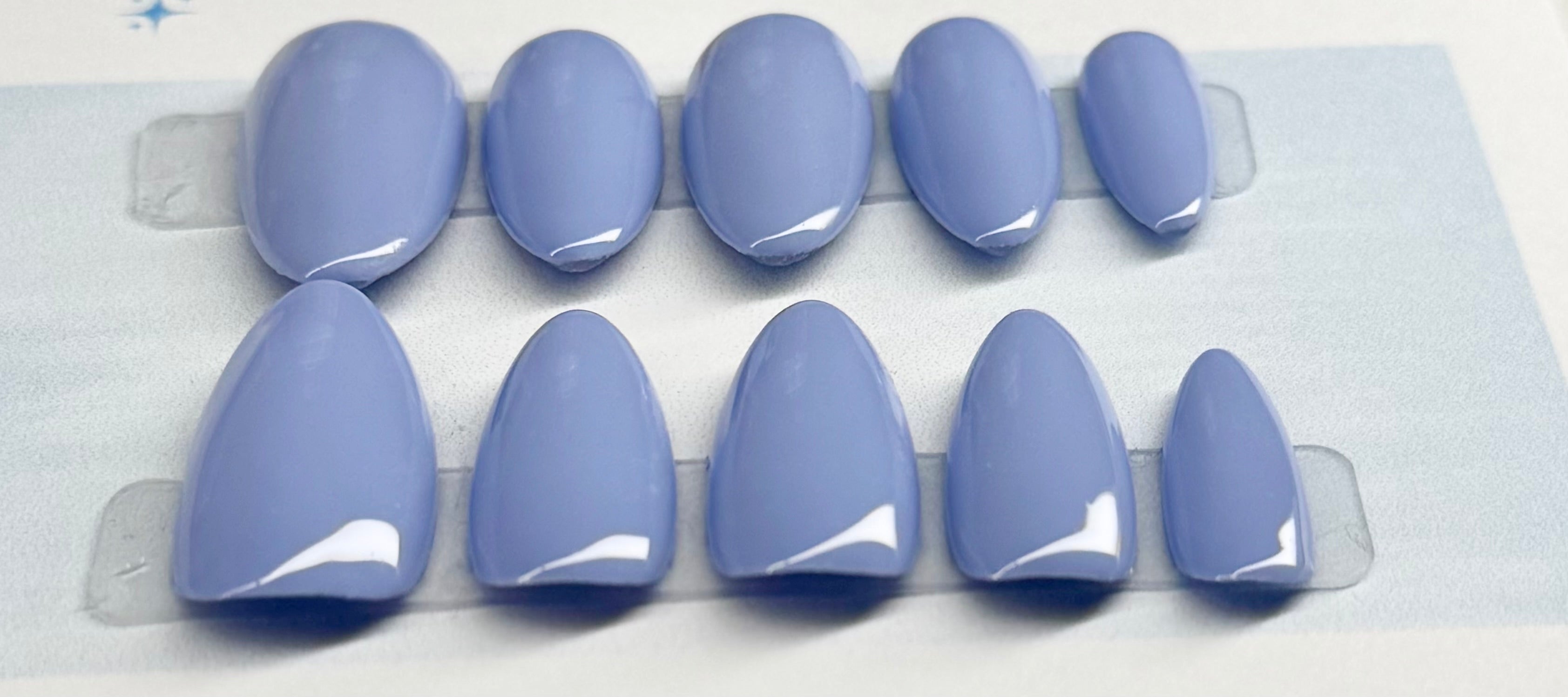 Set of llight blue colored false nails against a white background