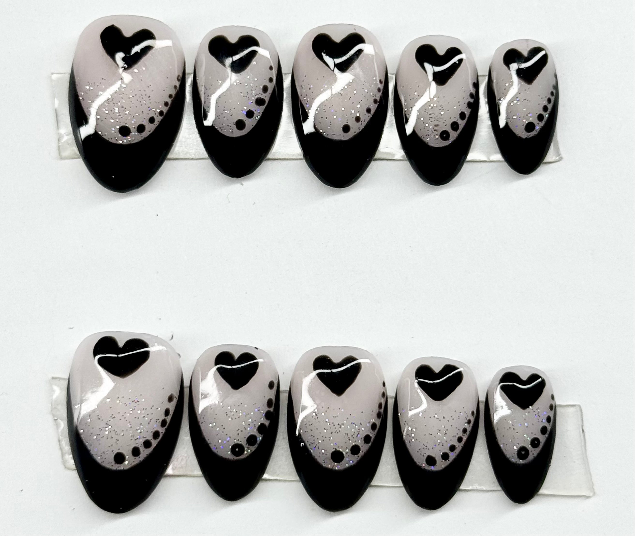 Nail art design with black hearts on a white background
