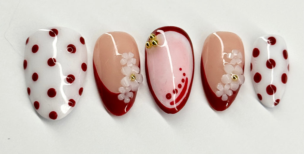 Set of five nail designs with polka dots and floral patterns on a white background
