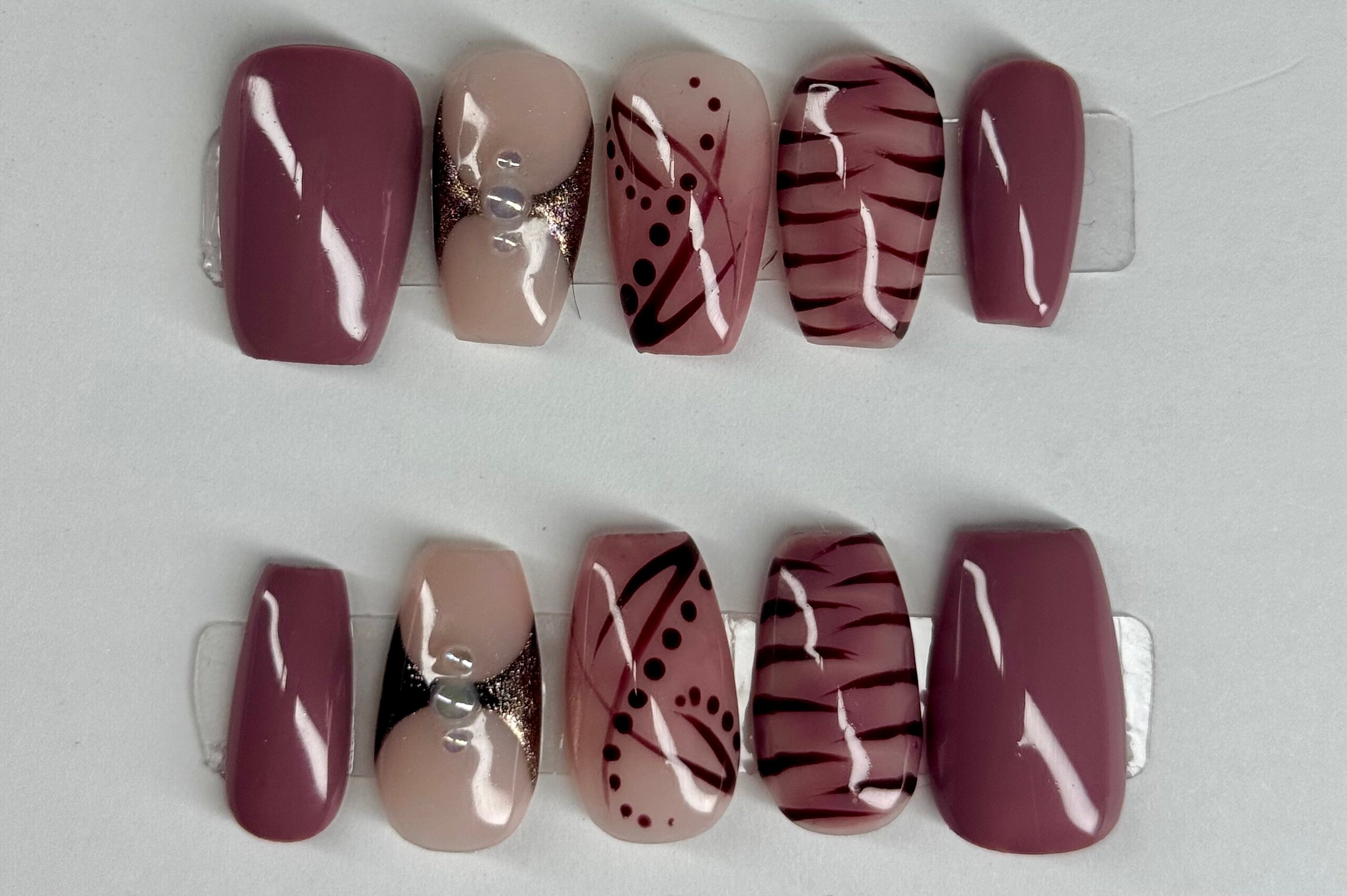 Set of nail designs on a clear display stand with a white background