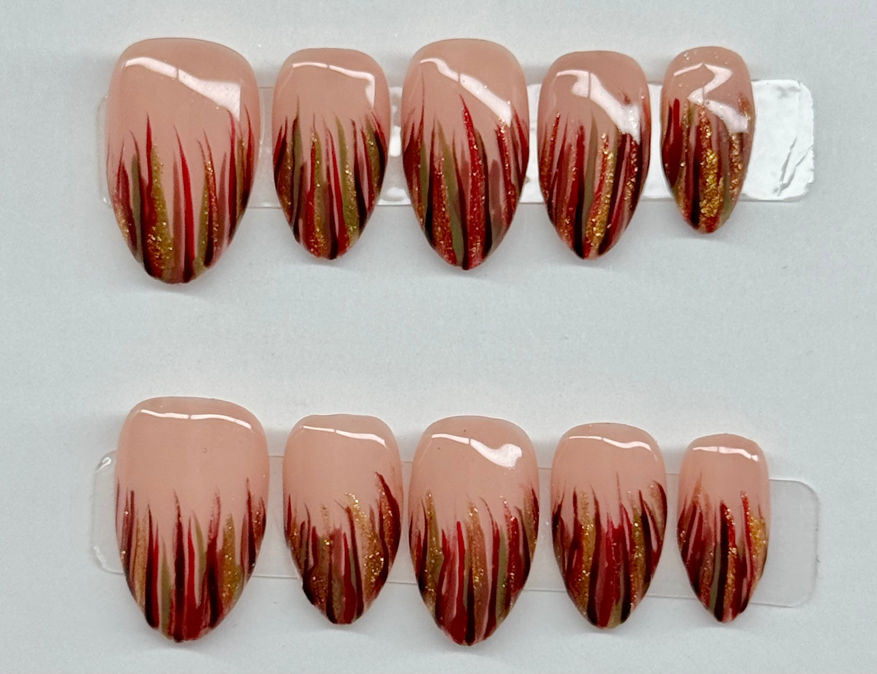 Set of nail extensions with a gradient design on a clear display stand.