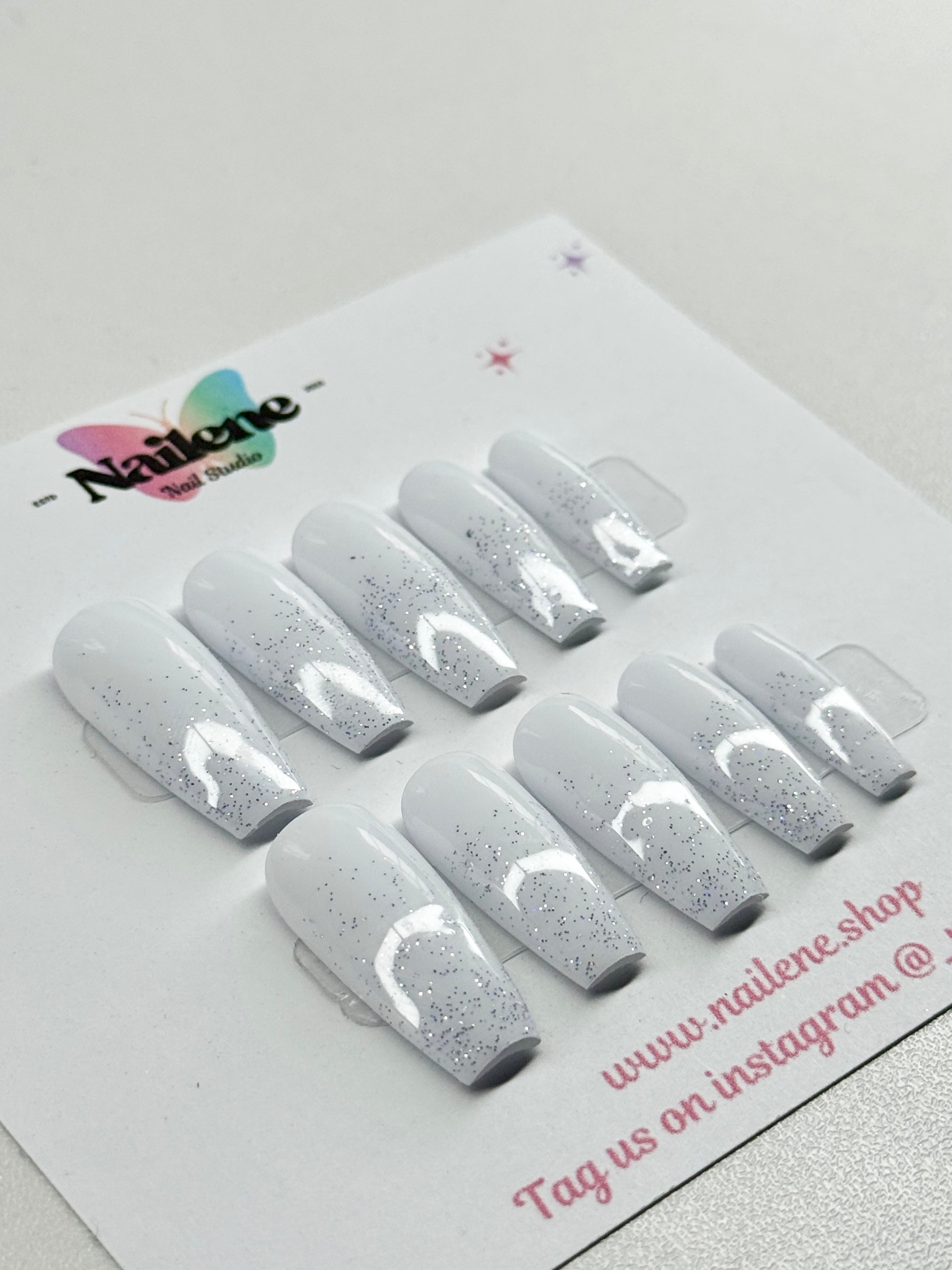 Set of silver glitter nail extensions on a white card with 'Nailene' branding.