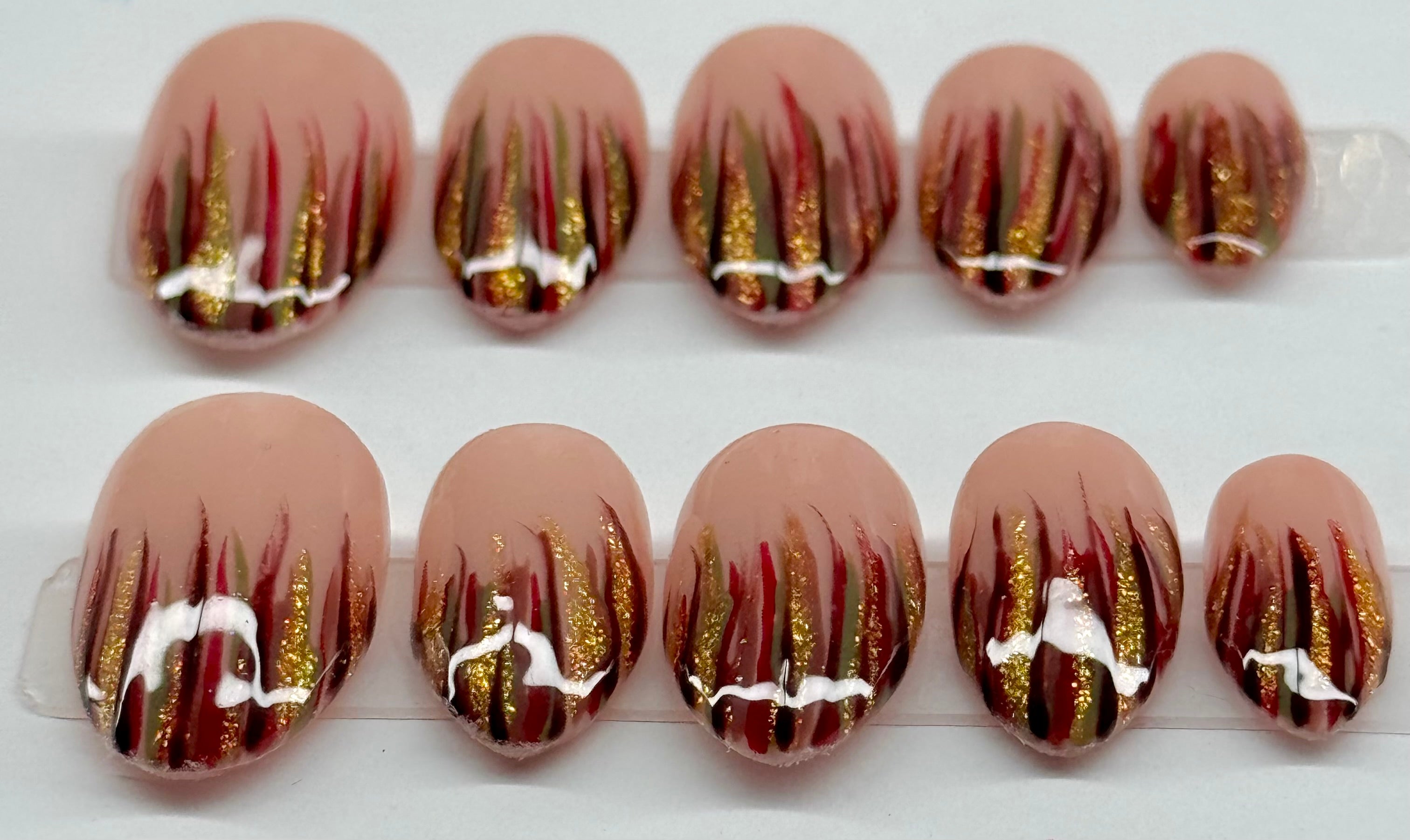 Nail art with gold and red design on a clear tray
