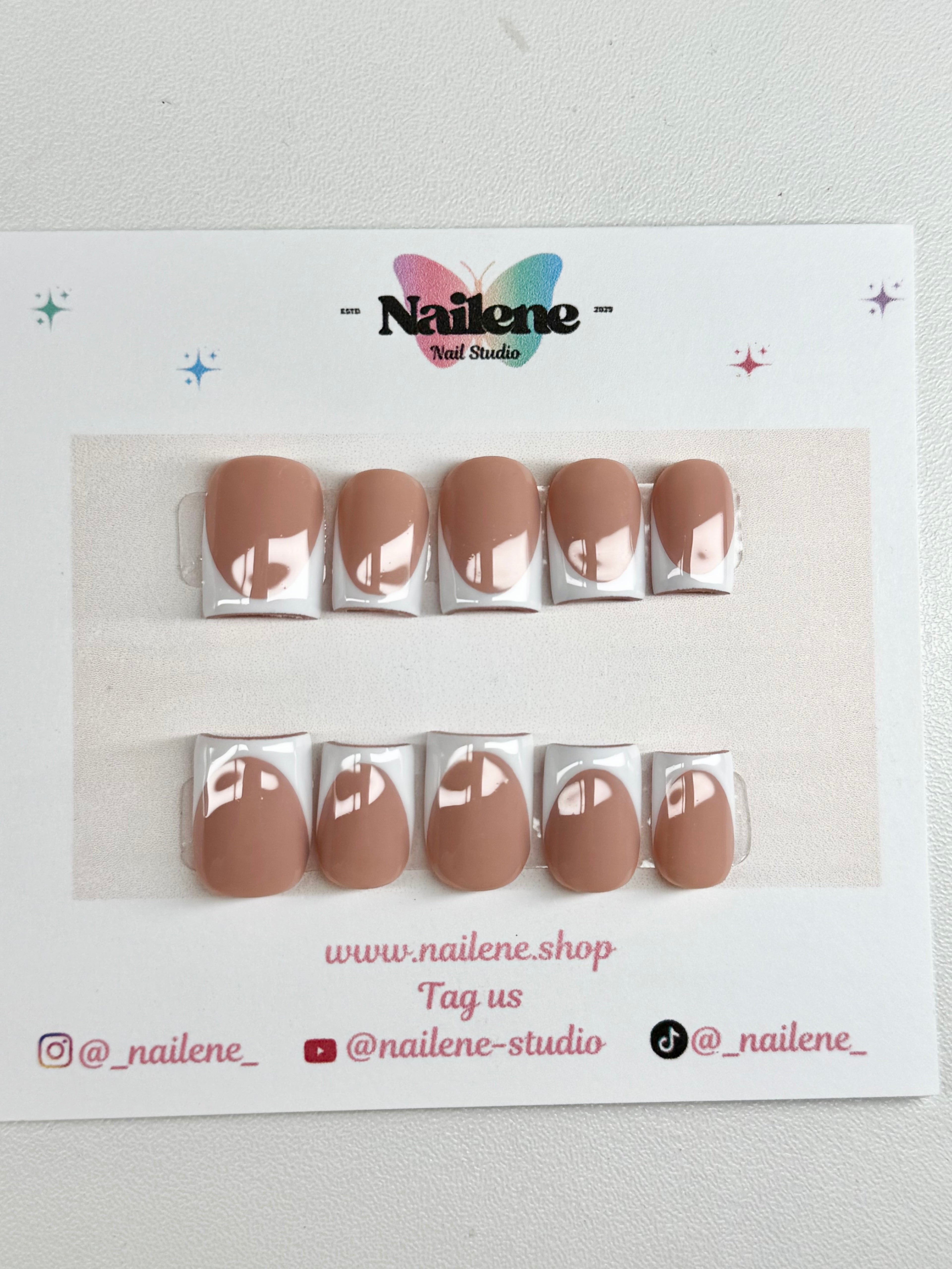 Set of brown nail extensions on a display card with Nailene branding.