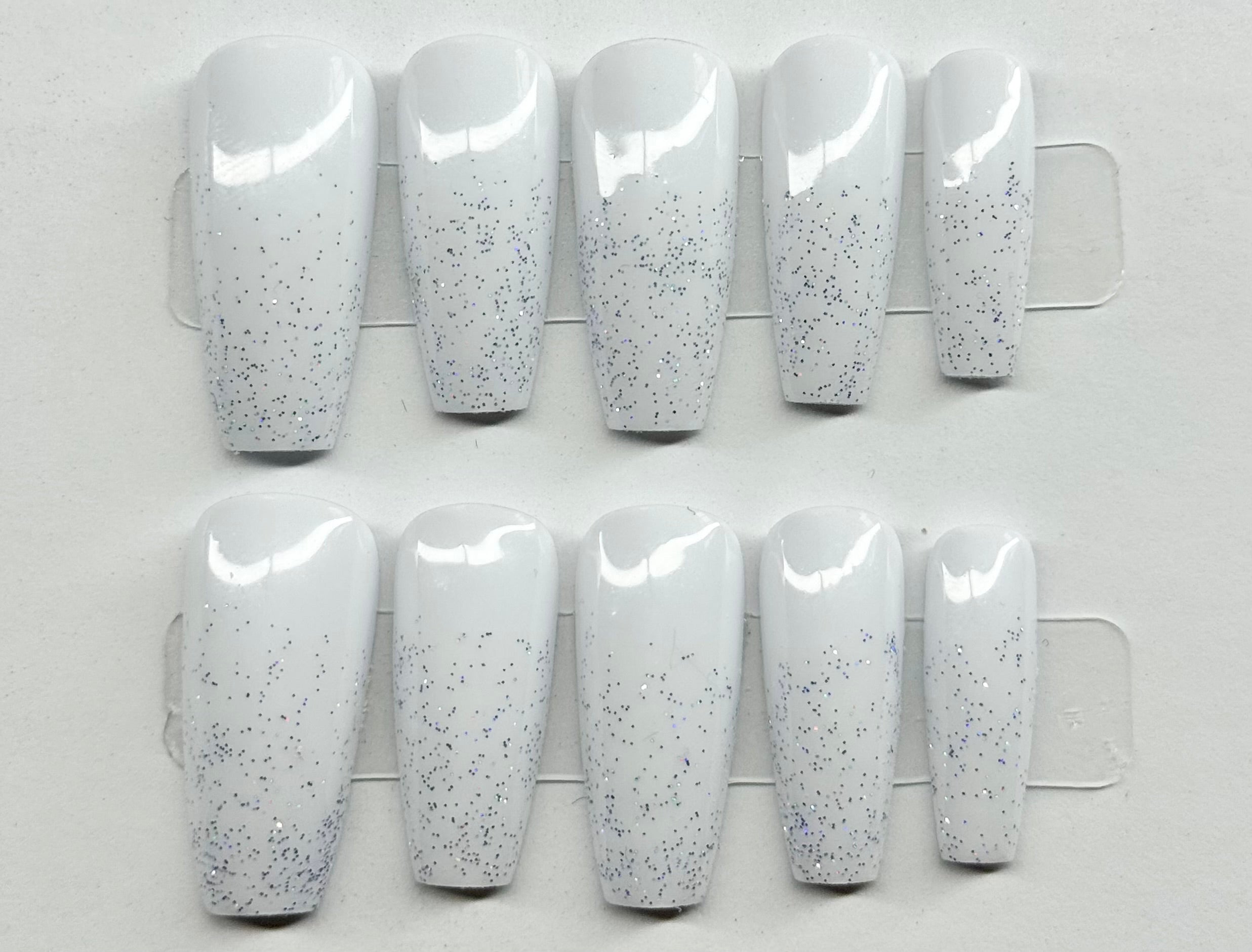 Set of white nail extensions with gray speckles on a white background