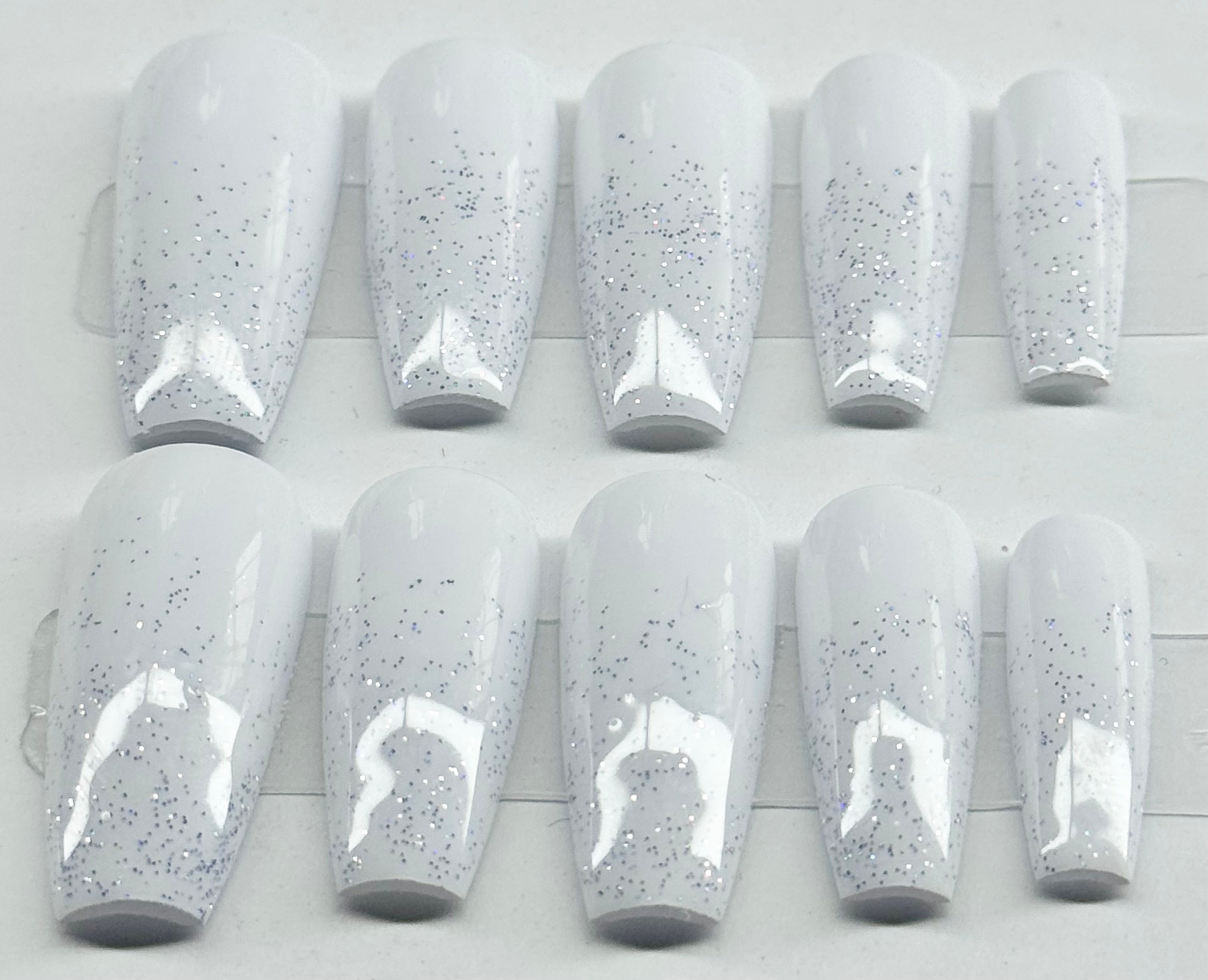 Set of white nail polish with glittery specks on a white background