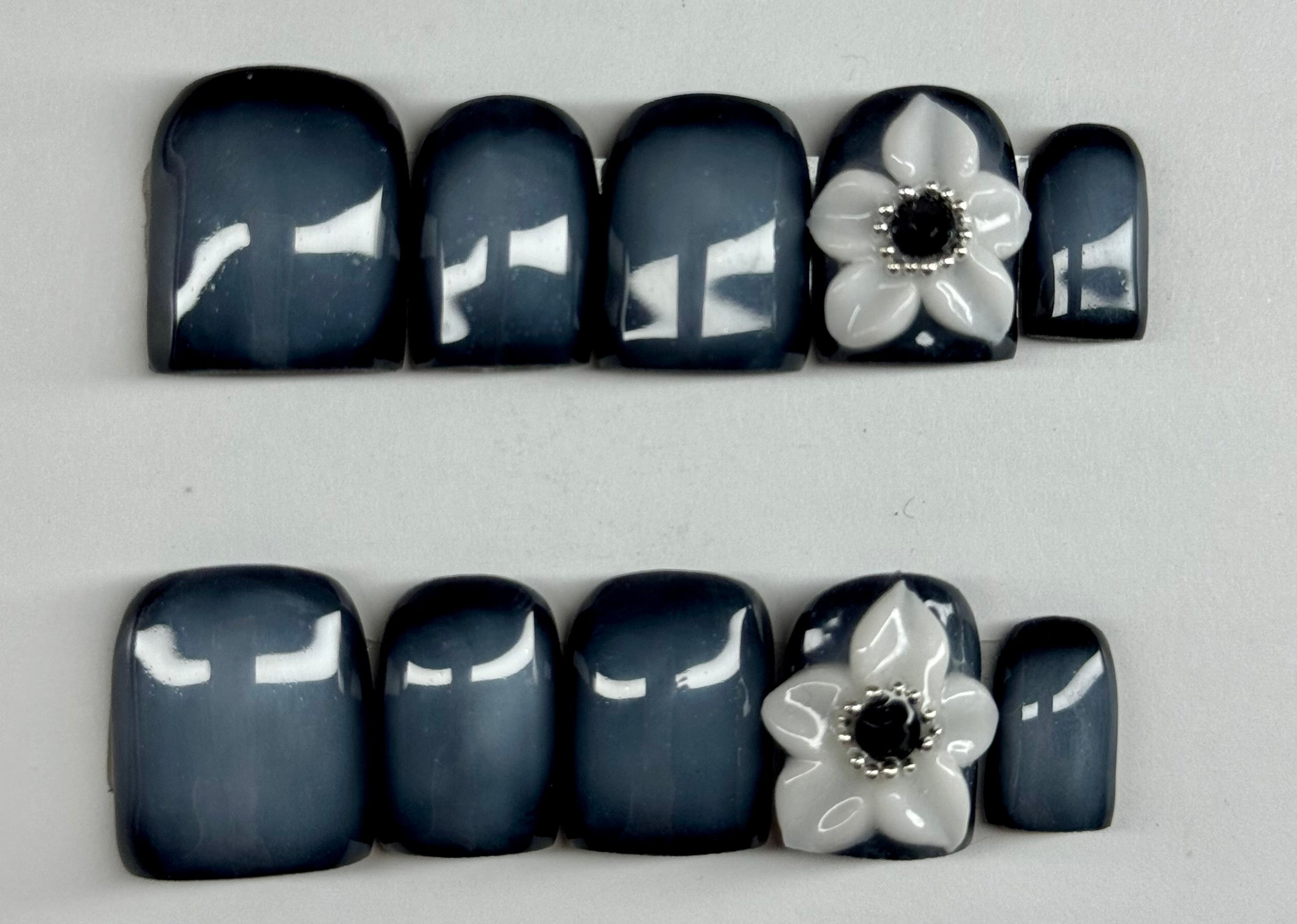 Nail art with black and white flowers on a light gray background