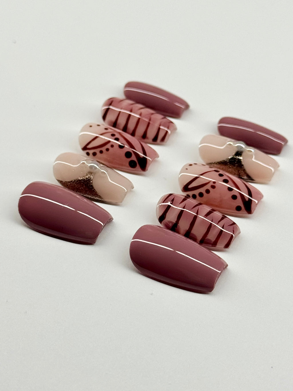 Set of decorative false nails with patterns on a light gray background