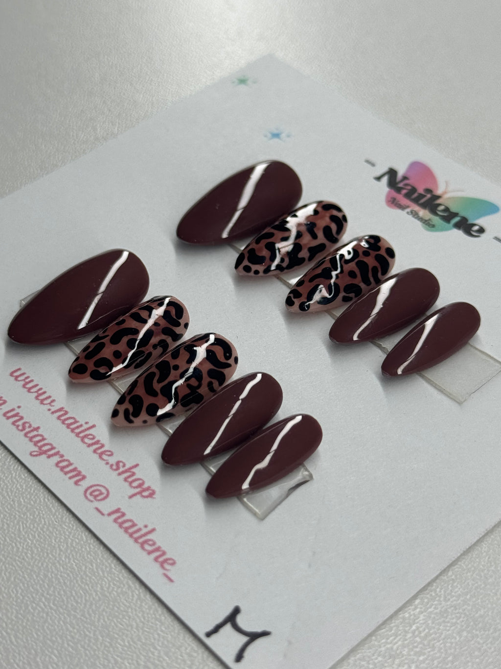 Set of brown and leopard print nails on a display card with Nailene branding.