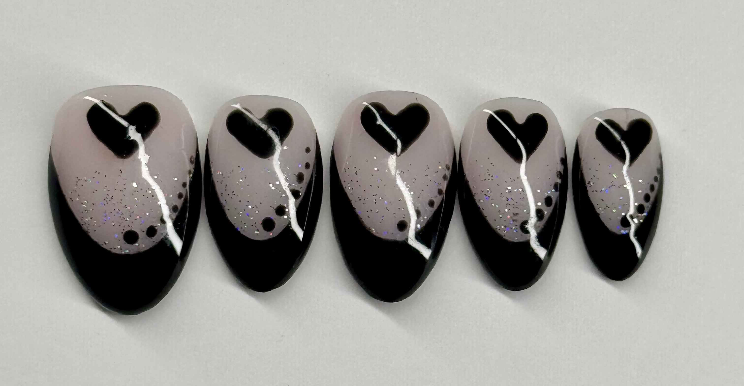 Set of five nail art designs with black hearts on a gray background