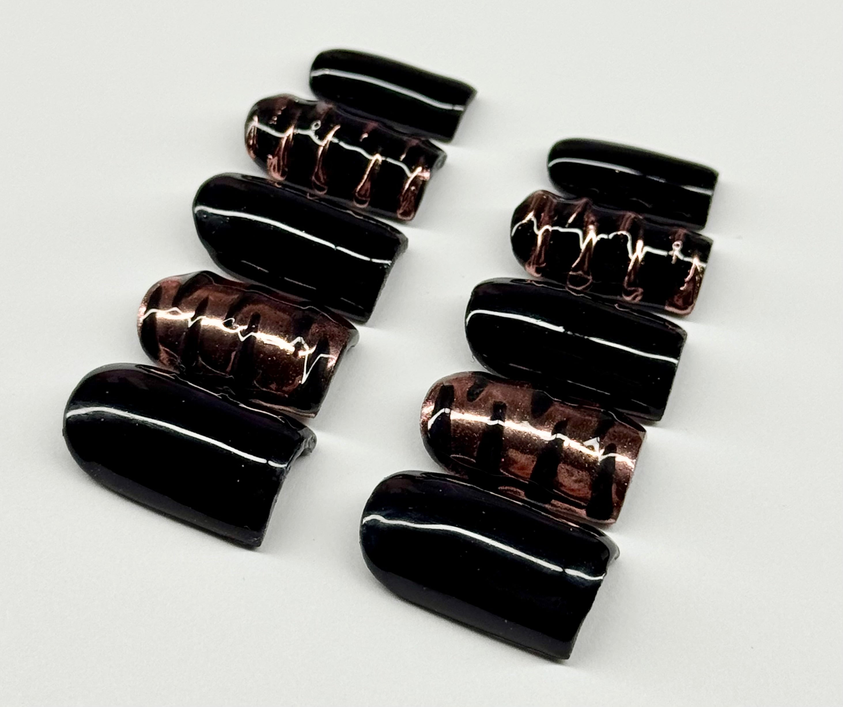 Set of black and brown nail extensions on a white background