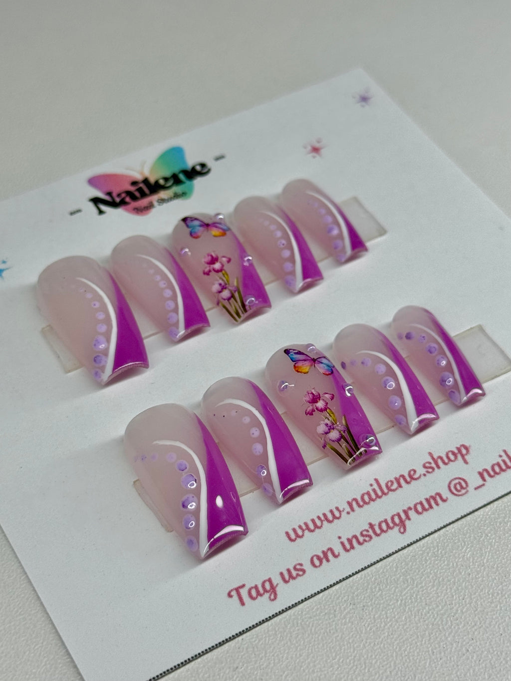 Set of purple and clear nail extensions on a white card with branding.