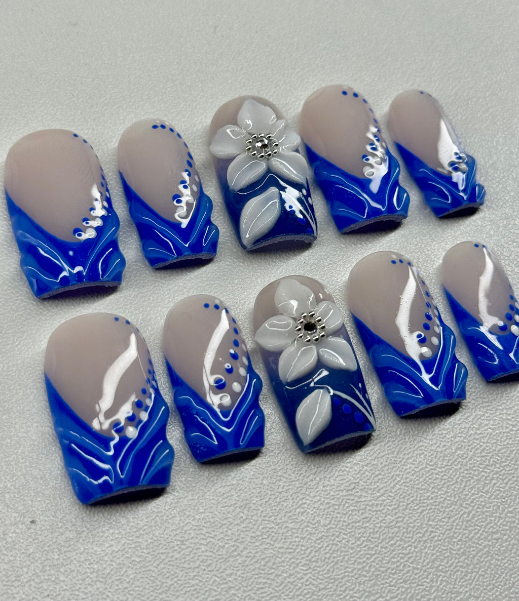 Set of blue and white nail art designs on a light nude background