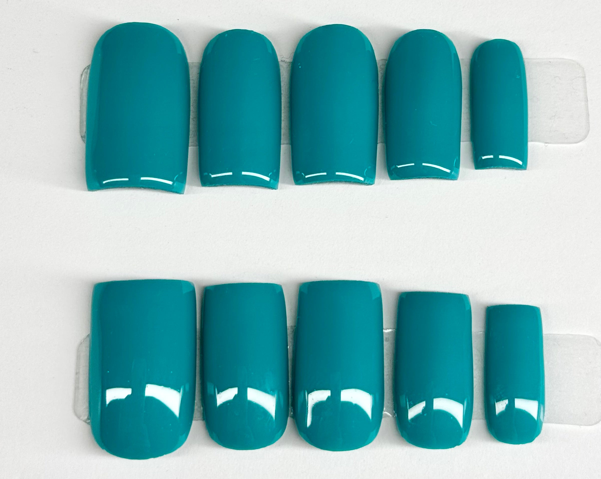 Set of teal nail polish strips on a white background