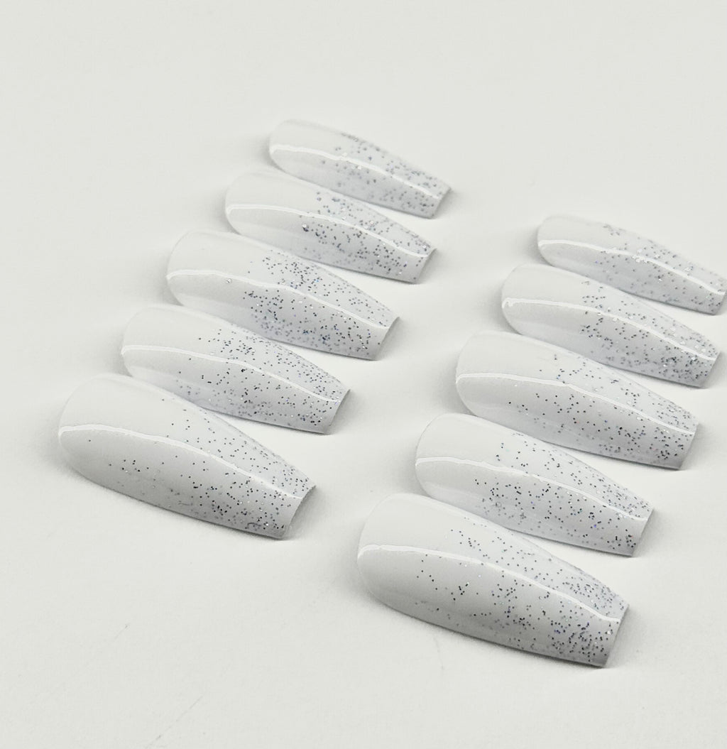 Set of white nail extensions with gray speckles on a light gray background