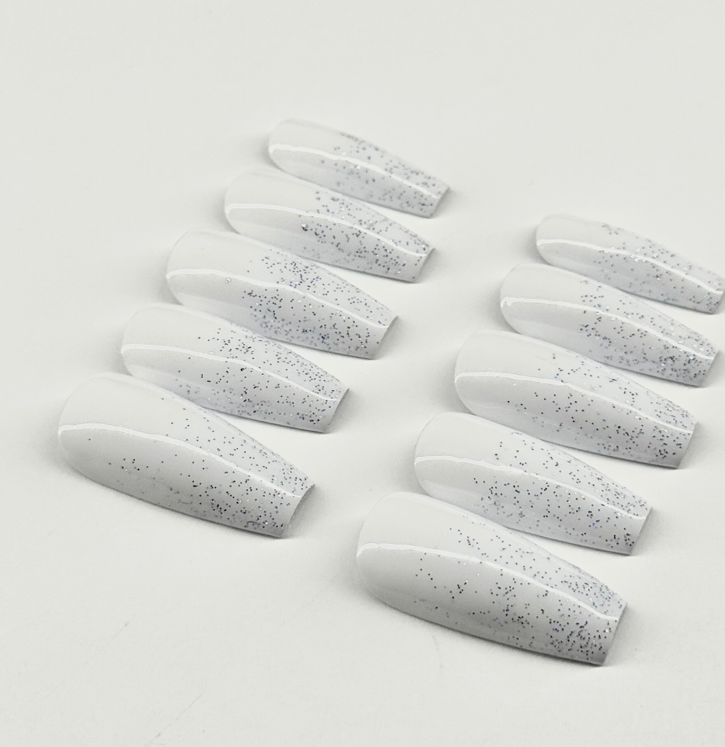 Set of white nail extensions with gray speckles on a light gray background