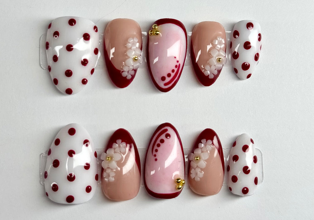 Set of decorative false nails with polka dots and floral patterns on a white background