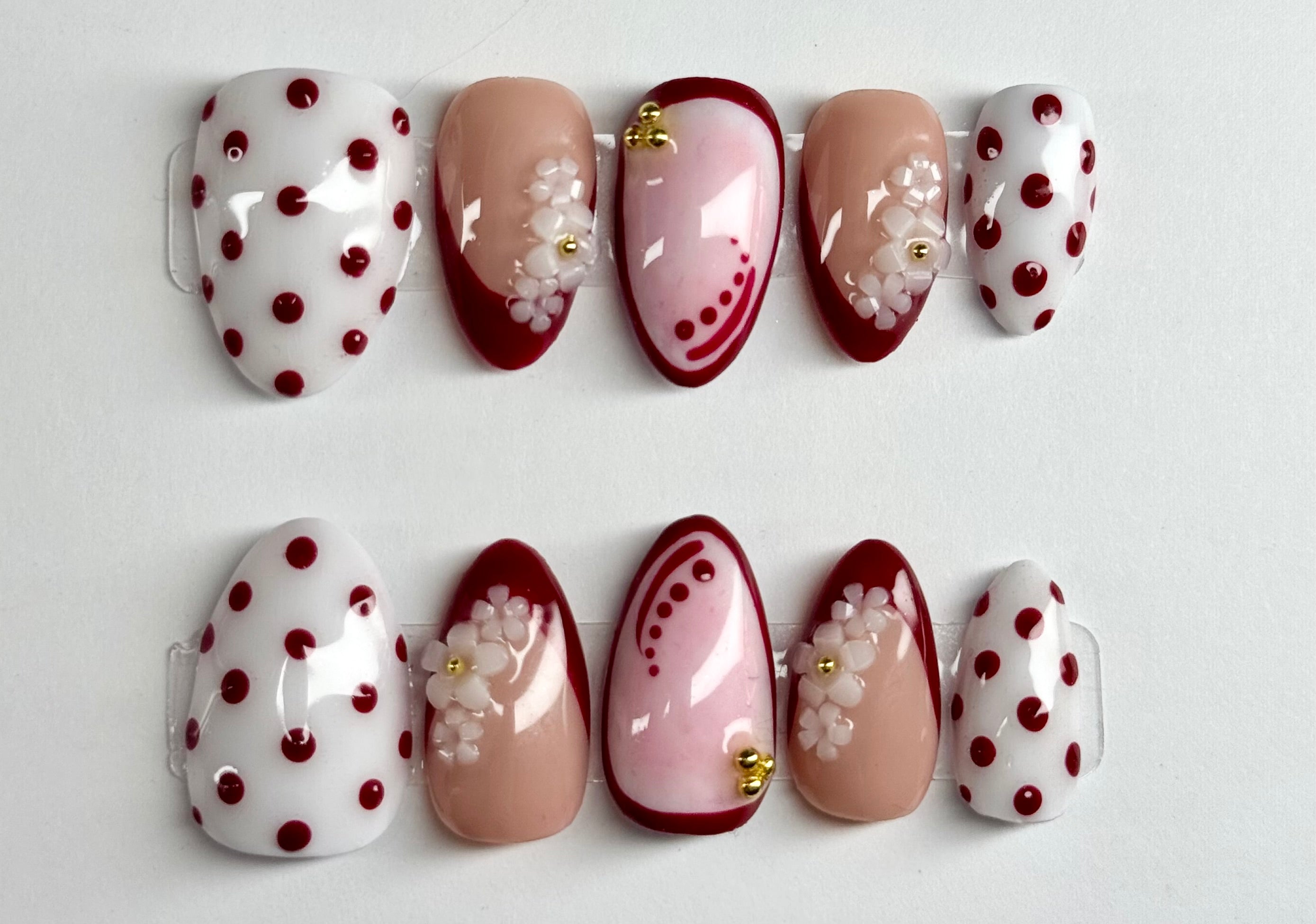Set of decorative false nails with polka dots and floral patterns on a white background