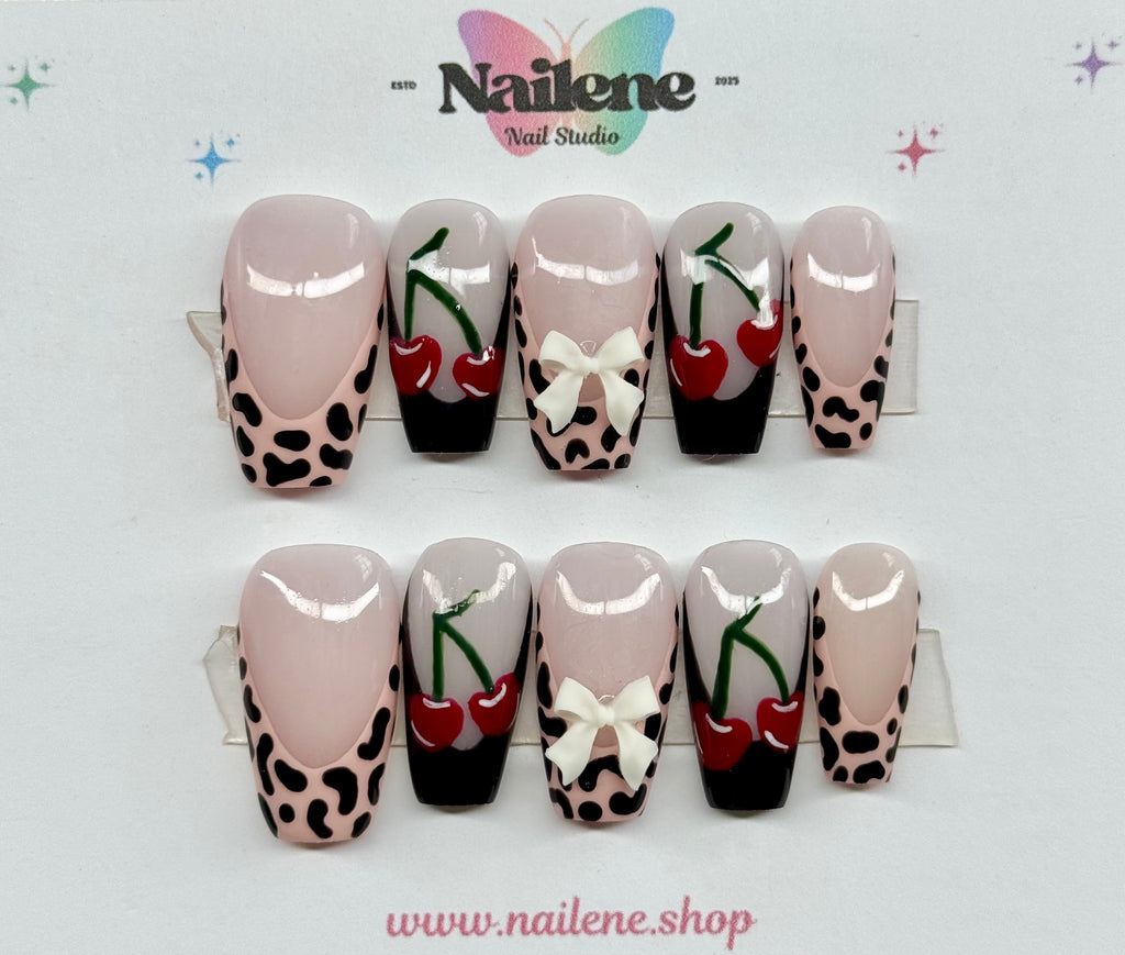 Nail art display with cherry and bow designs on a white background, featuring the Nailene brand.